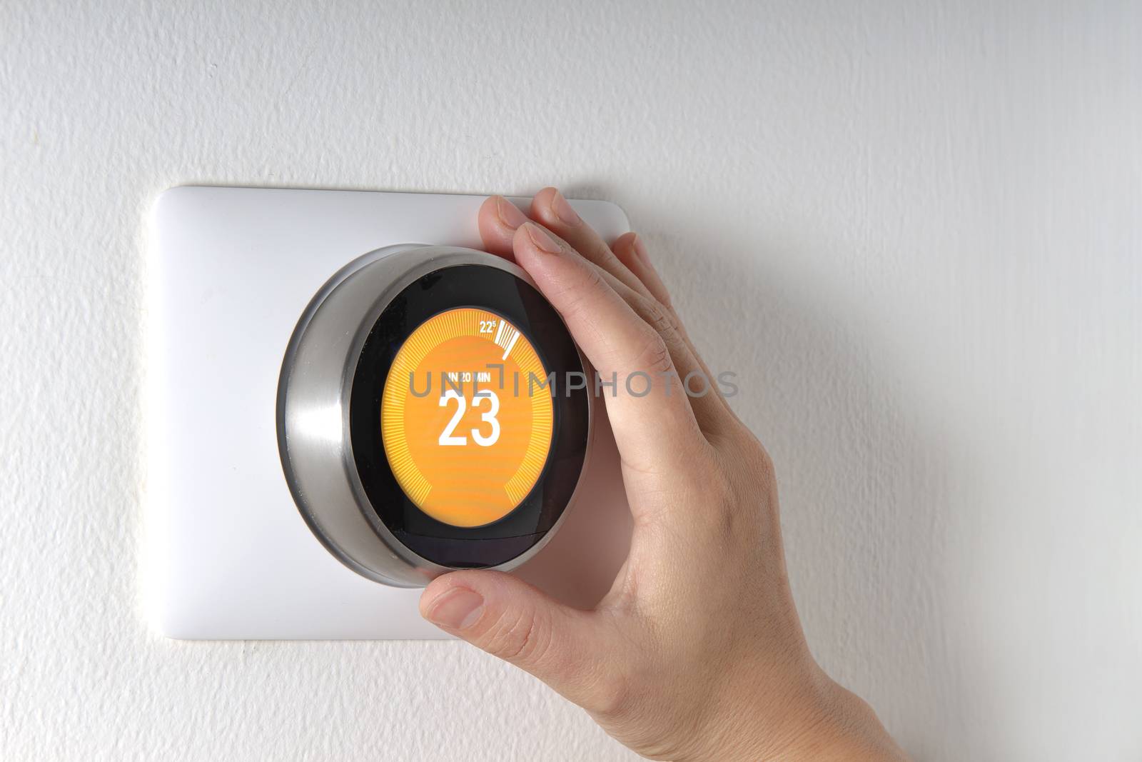 Smart Thermostat with a hand setting up the temperature by oasisamuel