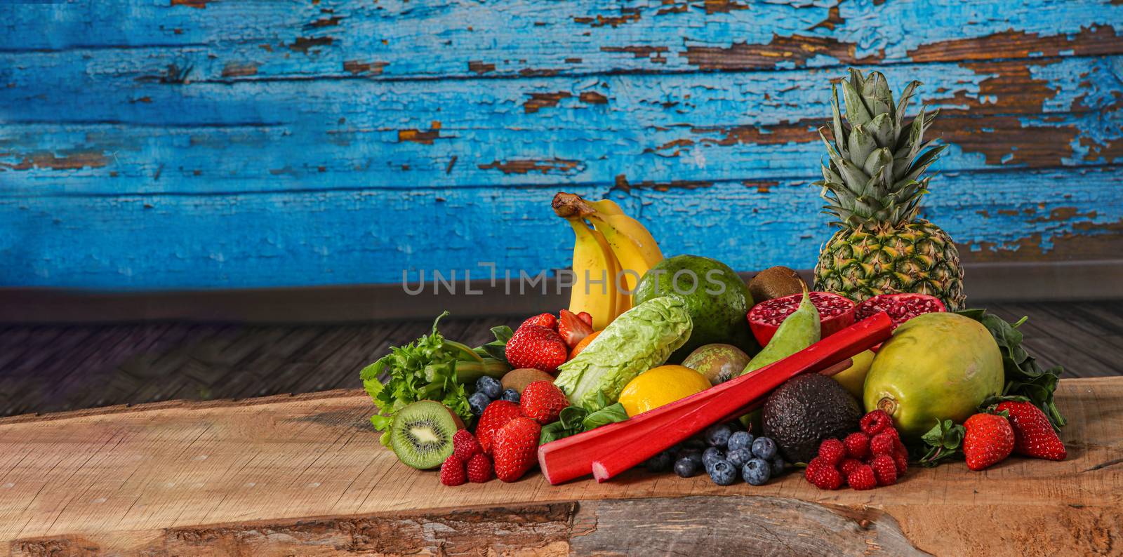 close up of healthy food and fruit with copy space. Blue background, with banana, pineapple, kiwi, blueberry, strawberry and avocado