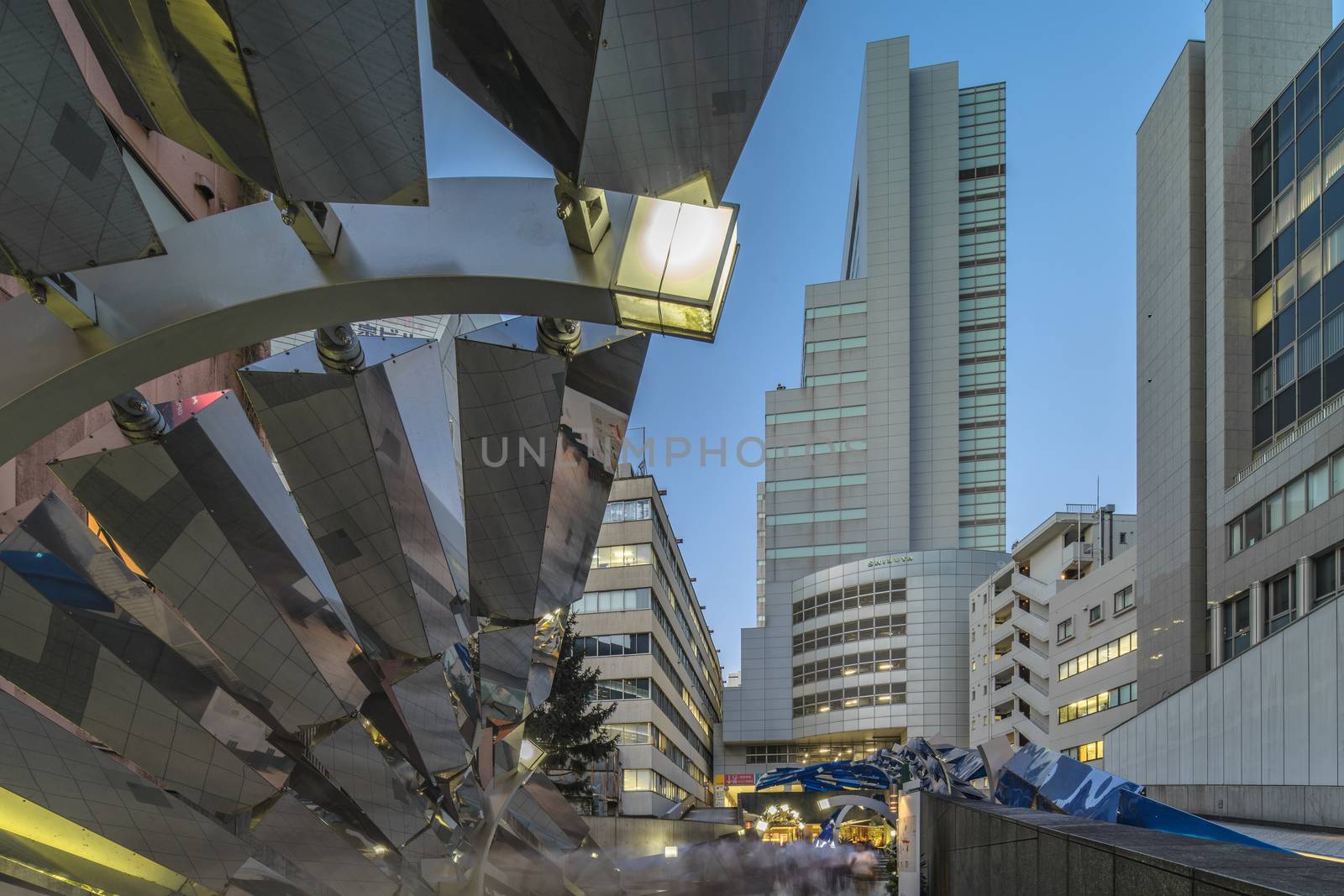 Futuristic architecture with mirroring panels swiveling in Shibuya district in Dogenzaka street leading to Shibuya Crossing Intersection in front of Shibuya Station in a summer evening.