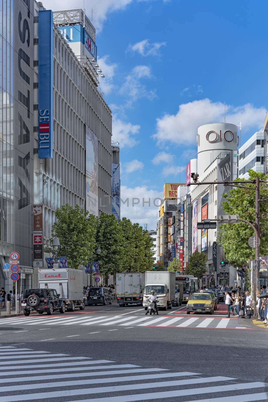 Shibuya Crossing Intersection in front of Shibuya Station on a bright day blue sky.