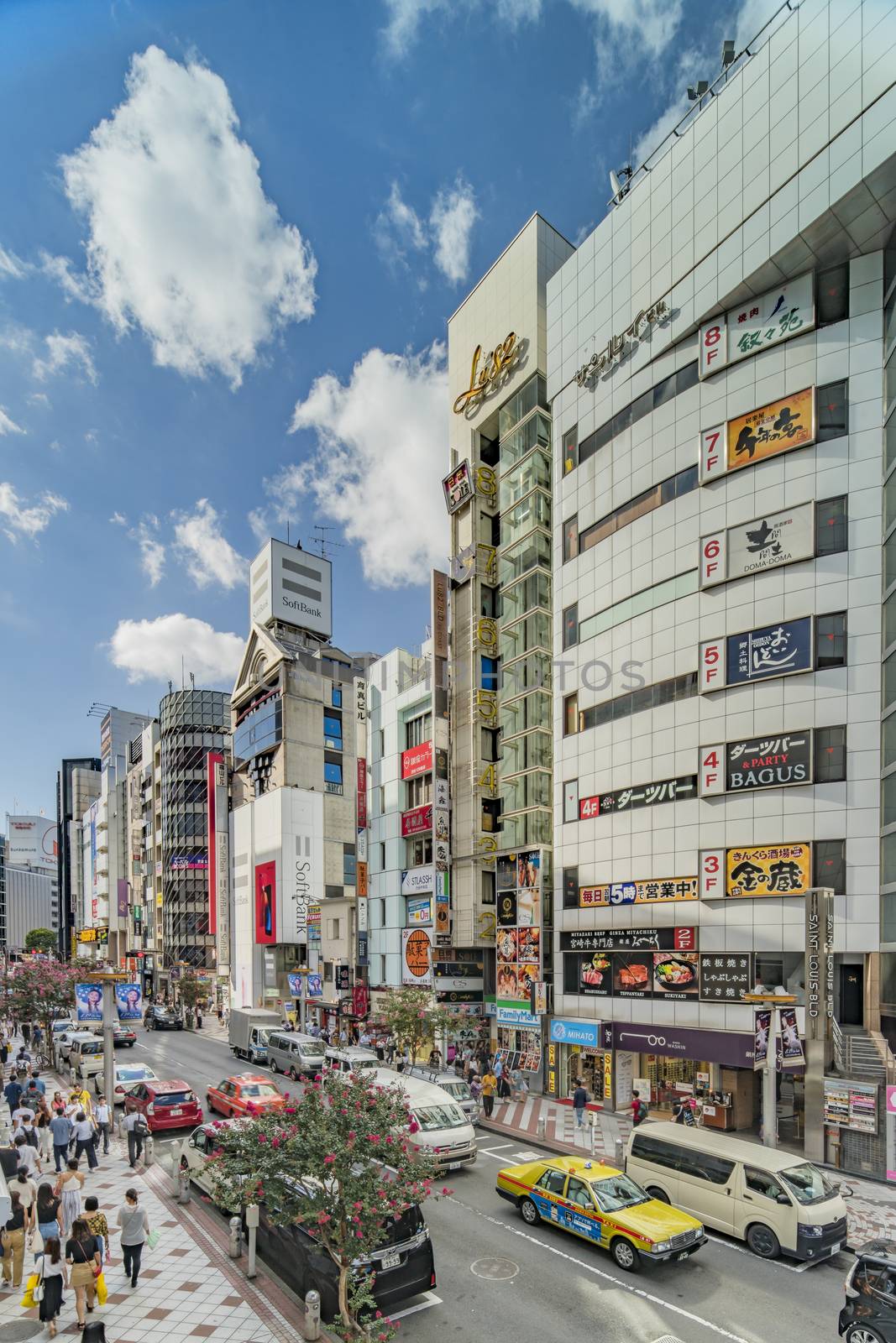 Shopping street leading to Shibuya Crossing Intersection in front of Shibuya Station on a bright day blue sky.