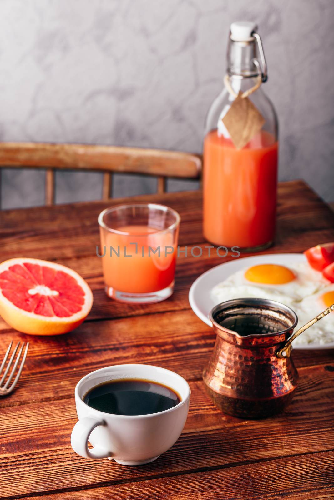 Breakfast with turkish coffee, fried eggs, juice and fruits over wooden table