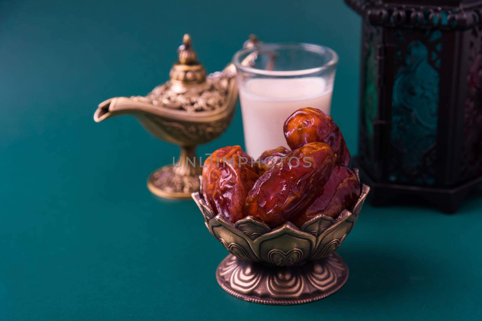 Ramadan Kareem fasting Food Concept, Bronze plate dates, milk, and lantern Aladdin lamp decoration, eid Arabian Muslim religious festival on a dark green background with copy space for text