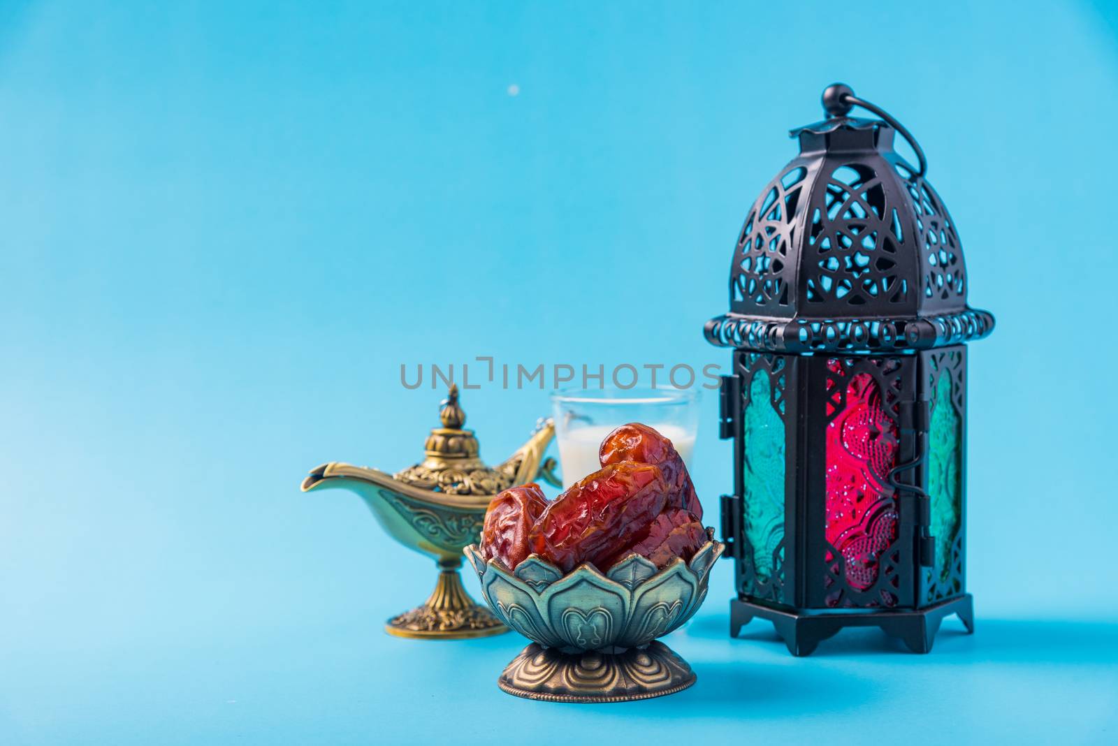 Ramadan Kareem fasting Food Concept, Bronze plate dates, milk, and lantern Aladdin lamp decoration, eid Arabian Muslim religious festival on a blue background with copy space for text