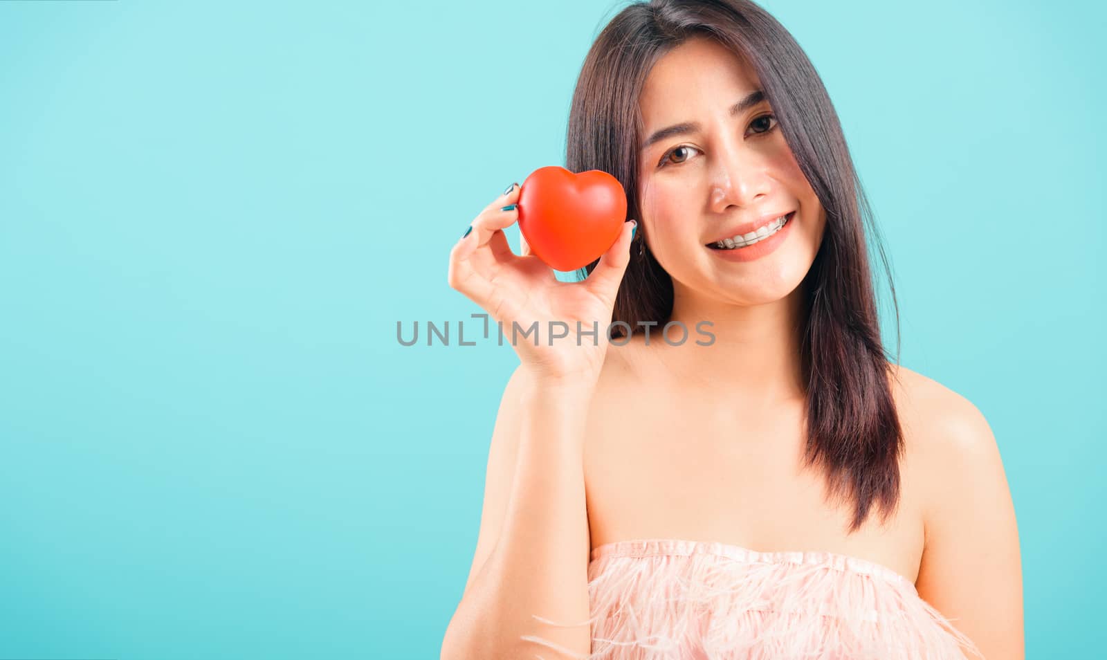 Portrait asian beautiful woman smiling her holding red heart on blue background, with copy space for text, valentine's day concept
