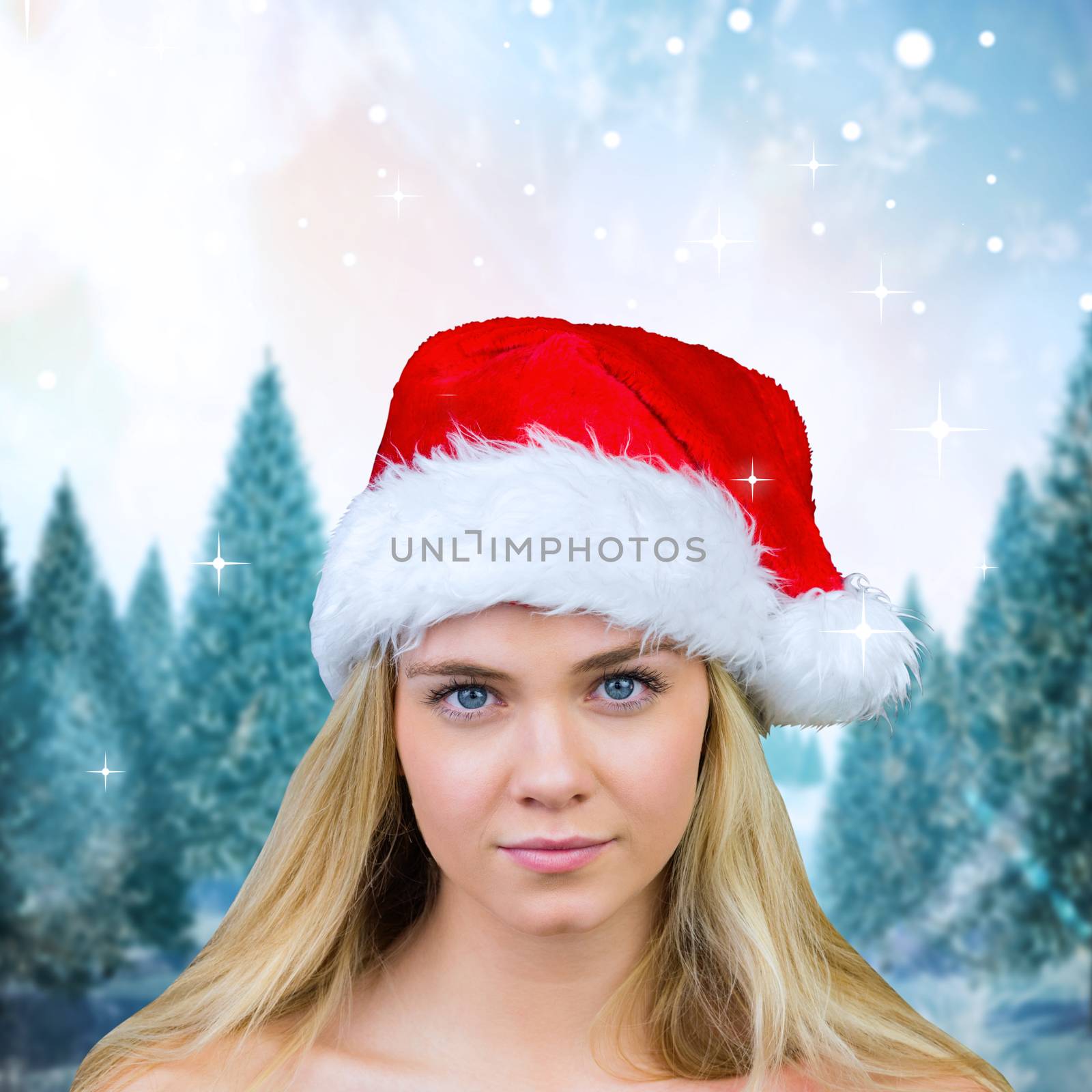 Blonde with bare shoulders in santa hat against snowy landscape with fir trees