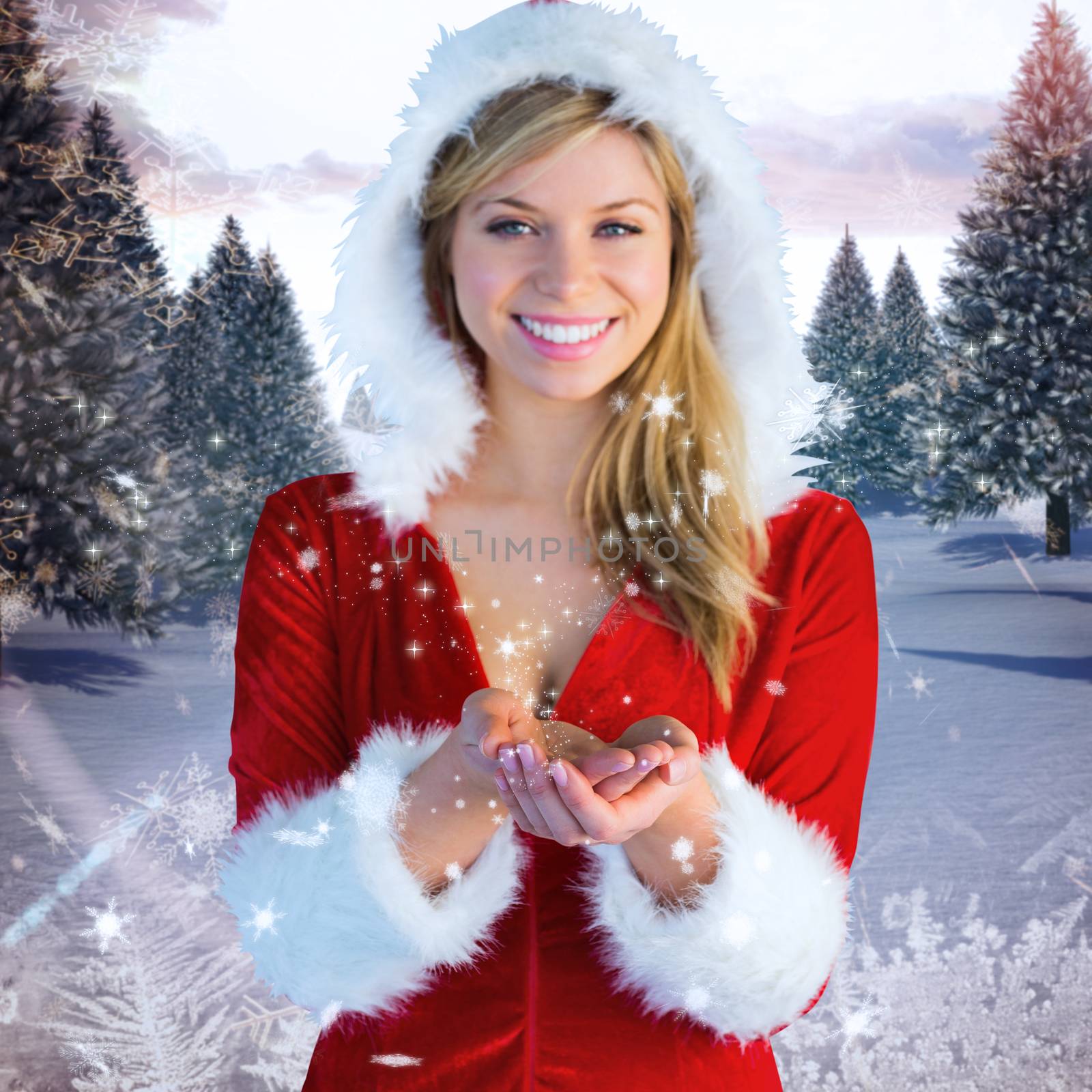 Pretty girl holding hands out in santa outfit against snowy landscape with fir trees