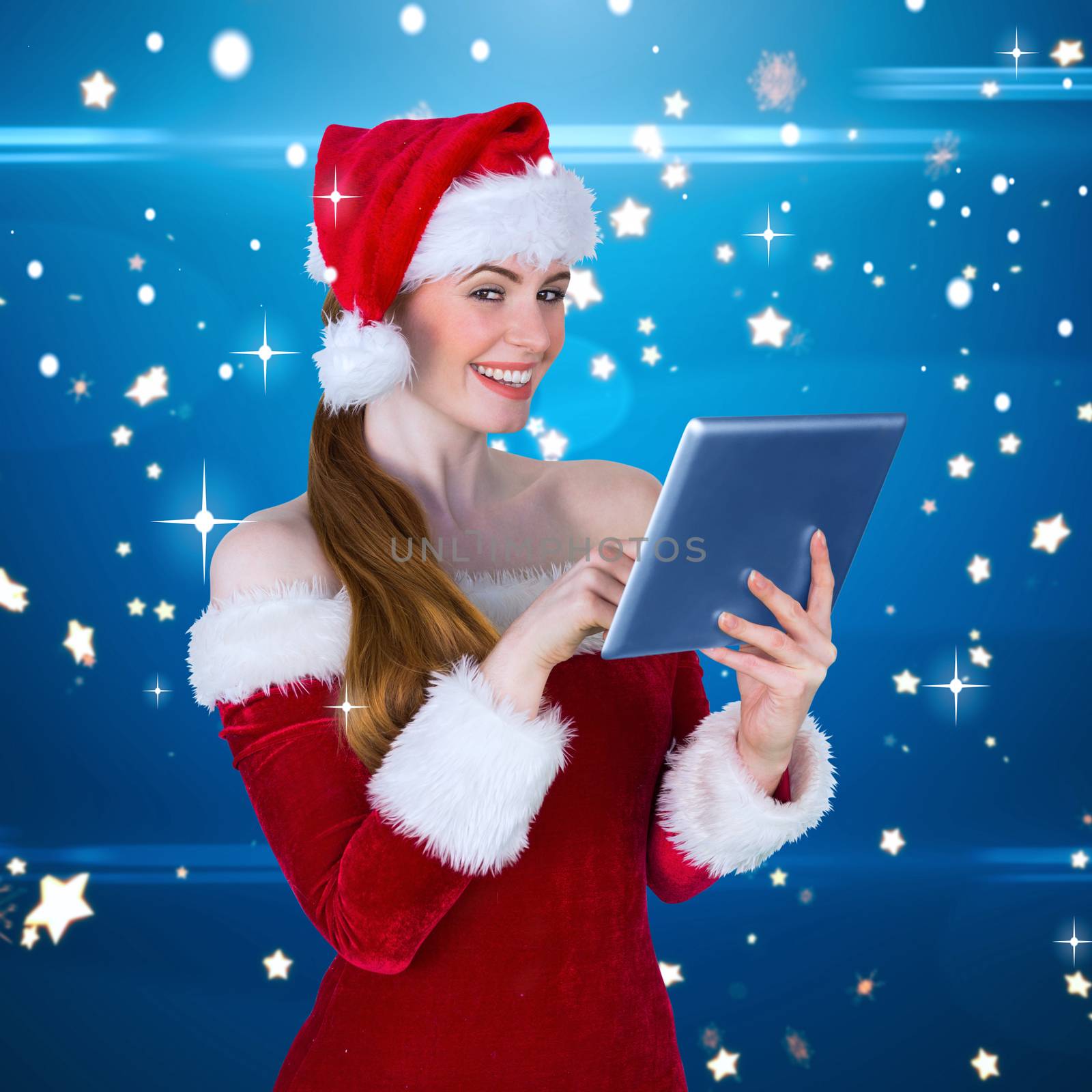 Pretty santa girl using tablet pc against bright star pattern on blue
