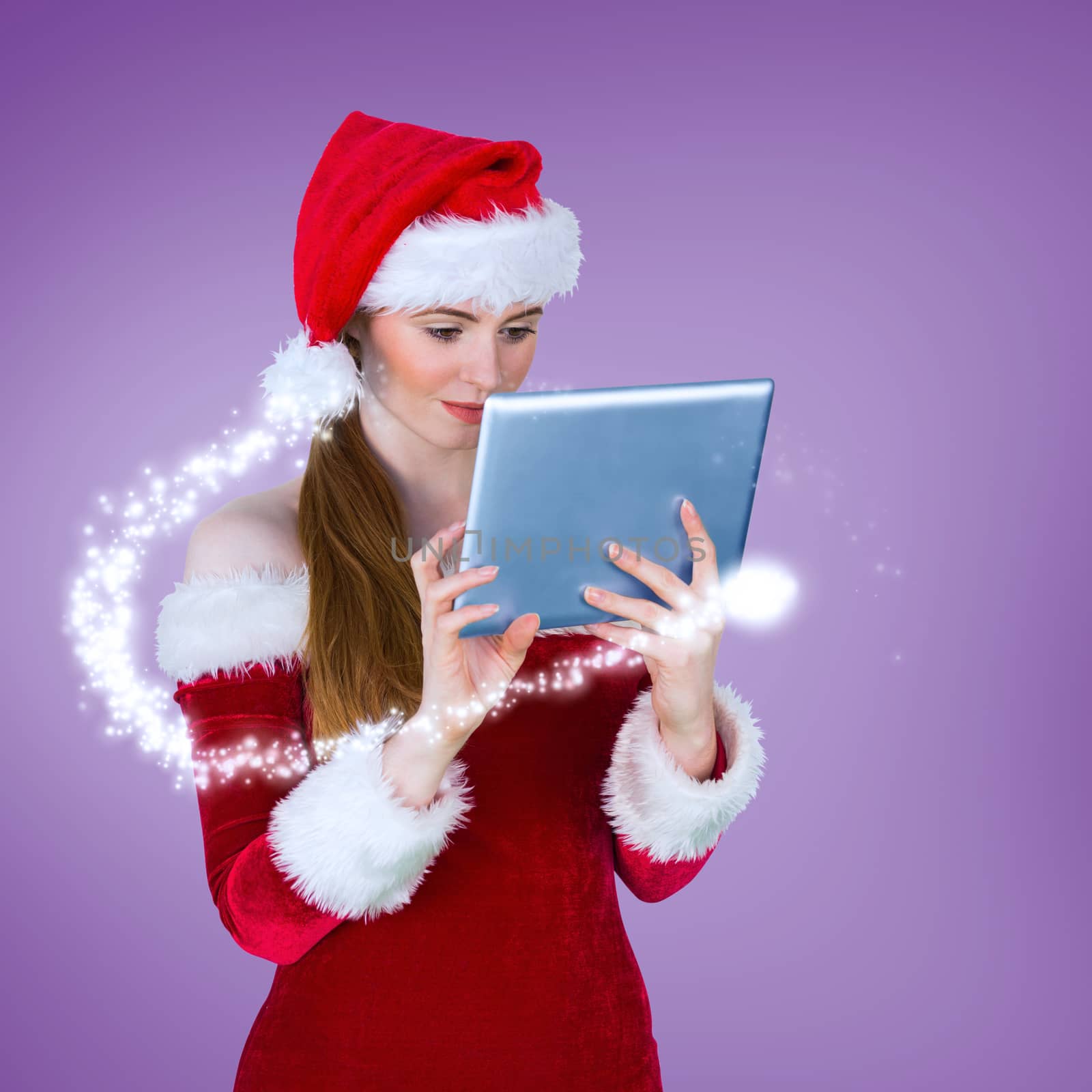 Pretty santa girl using tablet pc against purple vignette