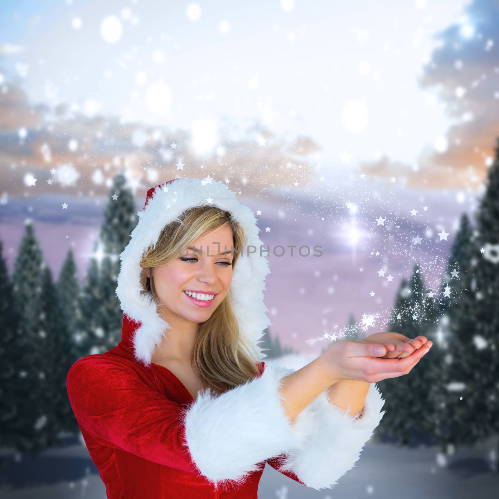 Pretty girl holding hands out in santa outfit against snowy landscape with fir trees