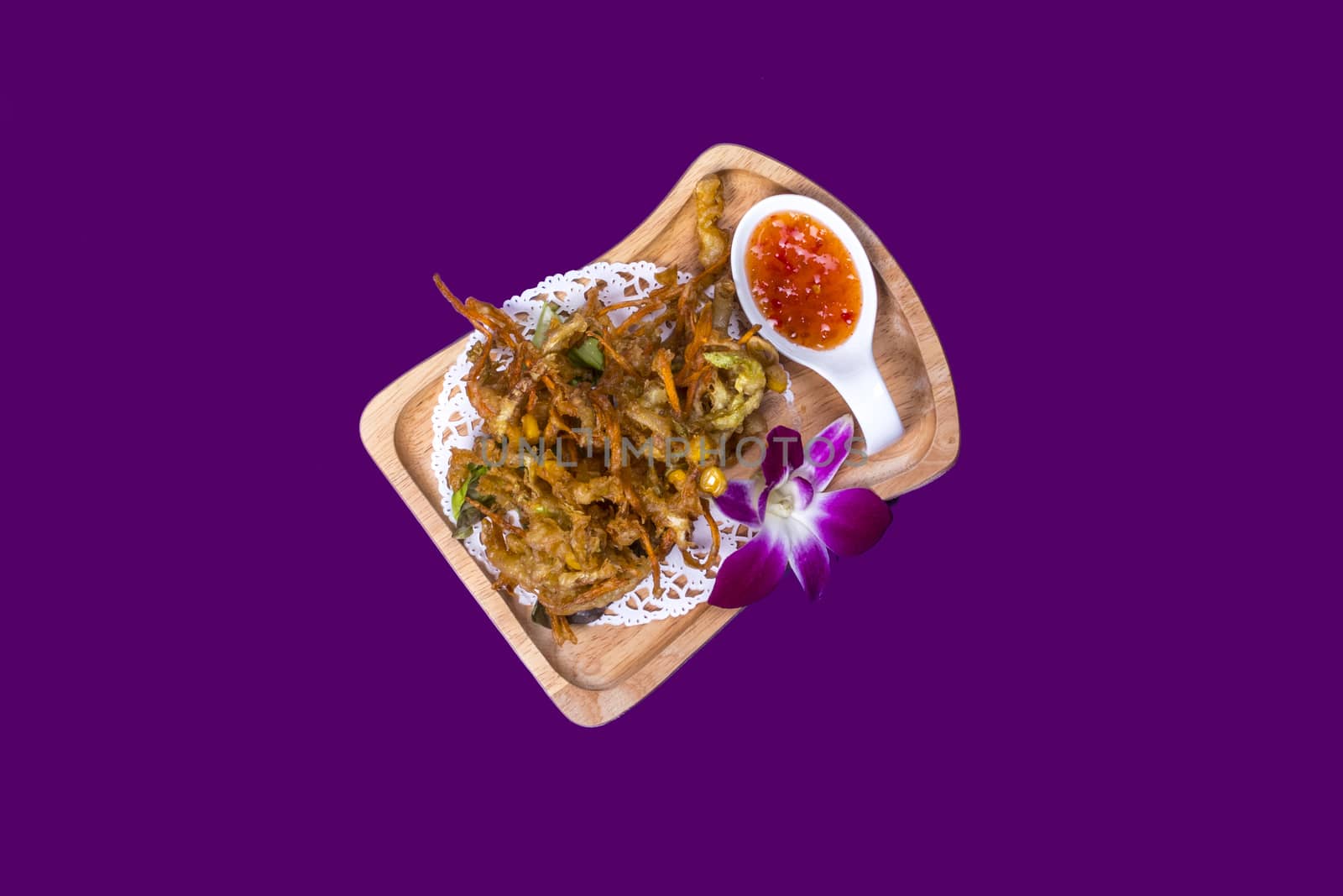 Thai food nicely prepared and displayed on purple background on wooden and white plates with to spicy sauces and shrimp