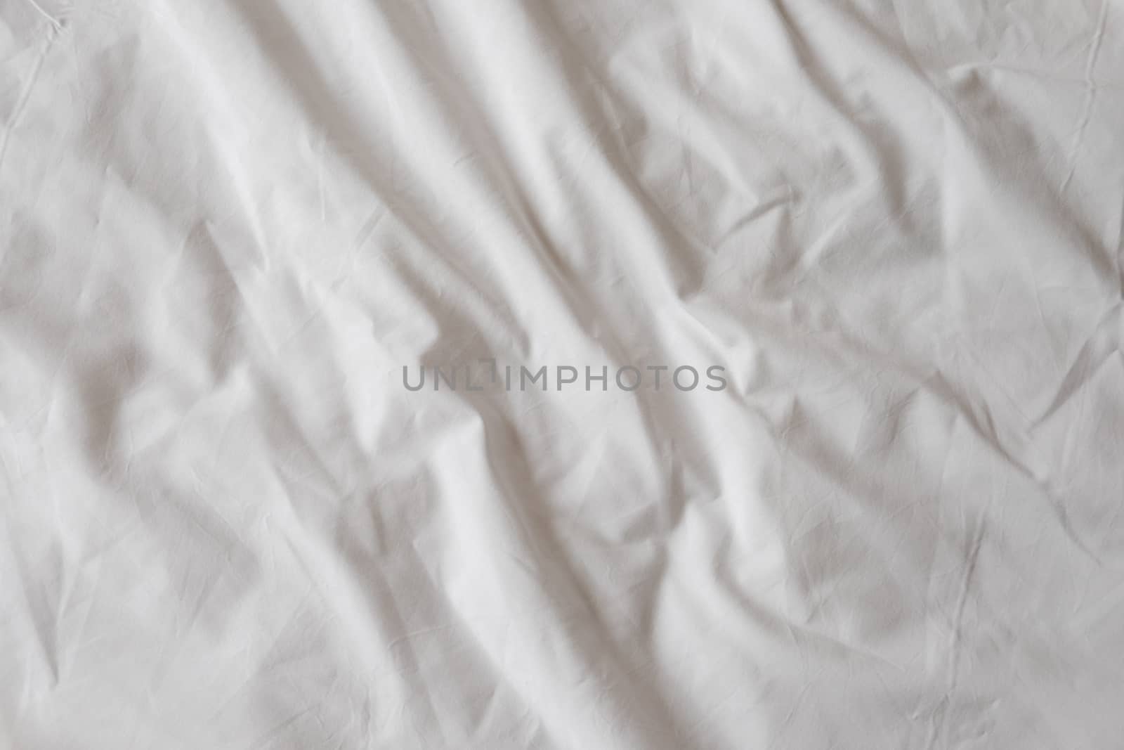 Background of white rumpled sheets. Bed linen with wrinkles in day light. Horizontal. Copy spase. Concept of rest, awakening, sleep. For social media, blog.