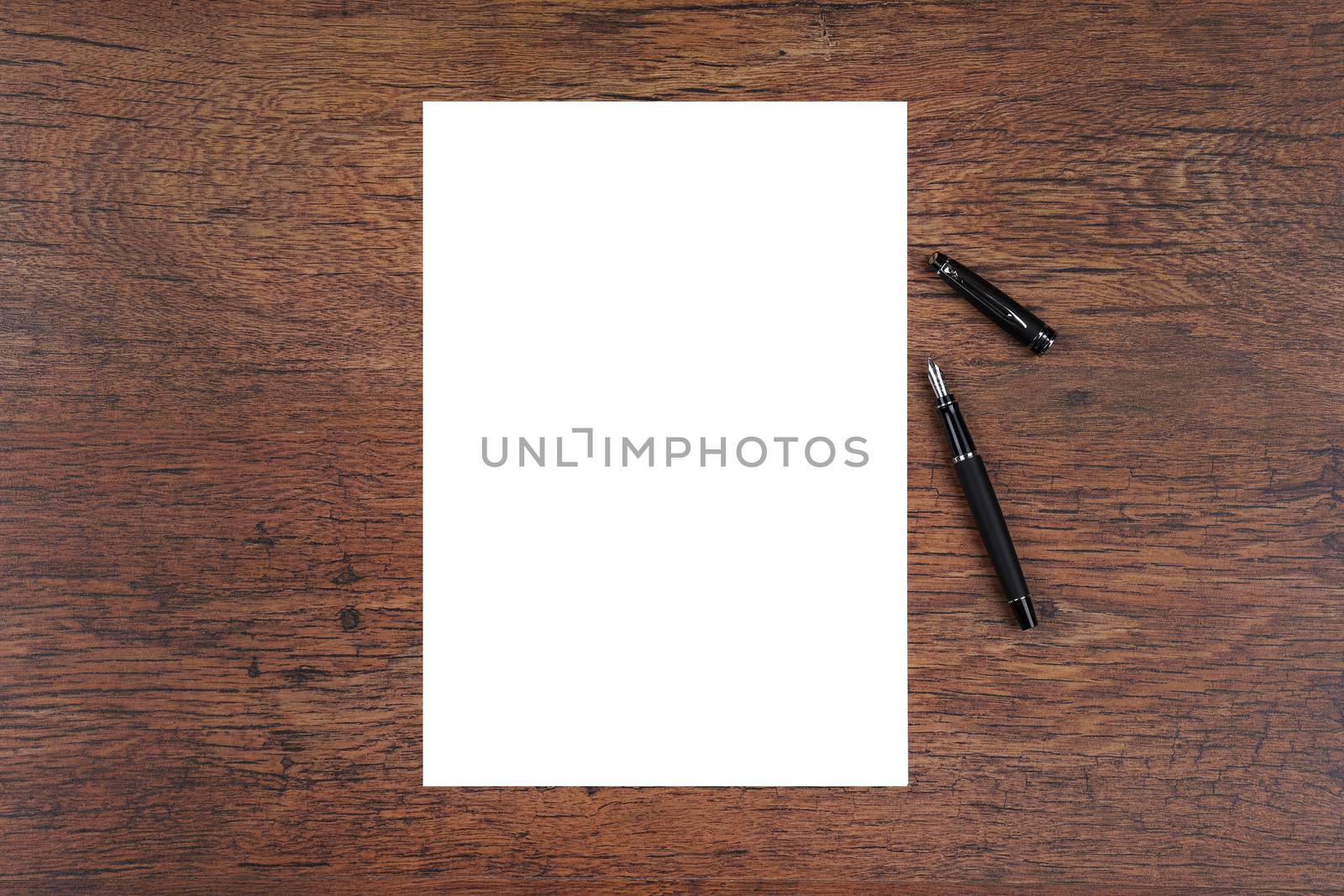 Ink fountain pen on dark wood with A4 white paper copy space by VivacityImages
