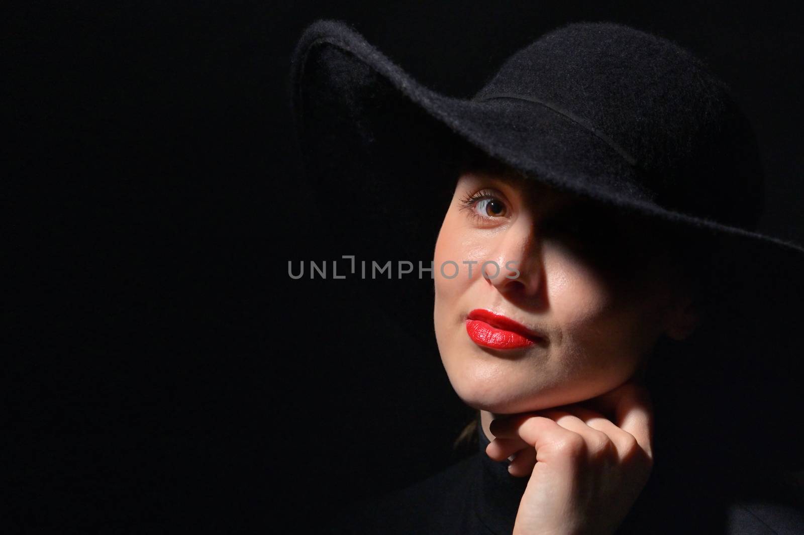 A Woman With Red Lips In A Black Hat On A Black Background