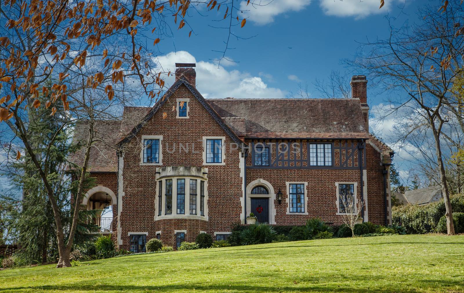 An old brick home with classic stone encased windows on a green grass lawn