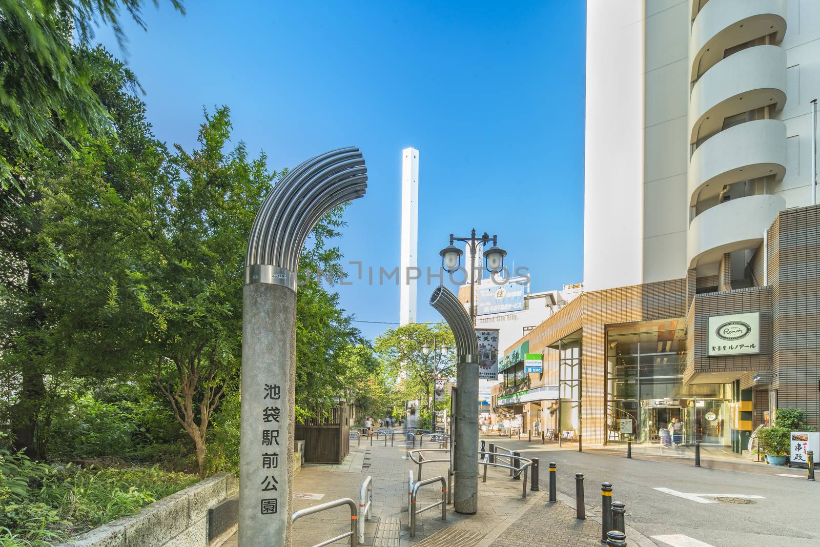 Entrance gate of the Ikebukuro Station Park with in background the Toshima Ward Cleanup Factory chimney in the Ikebukuro district at north of Tokyo, Japan.