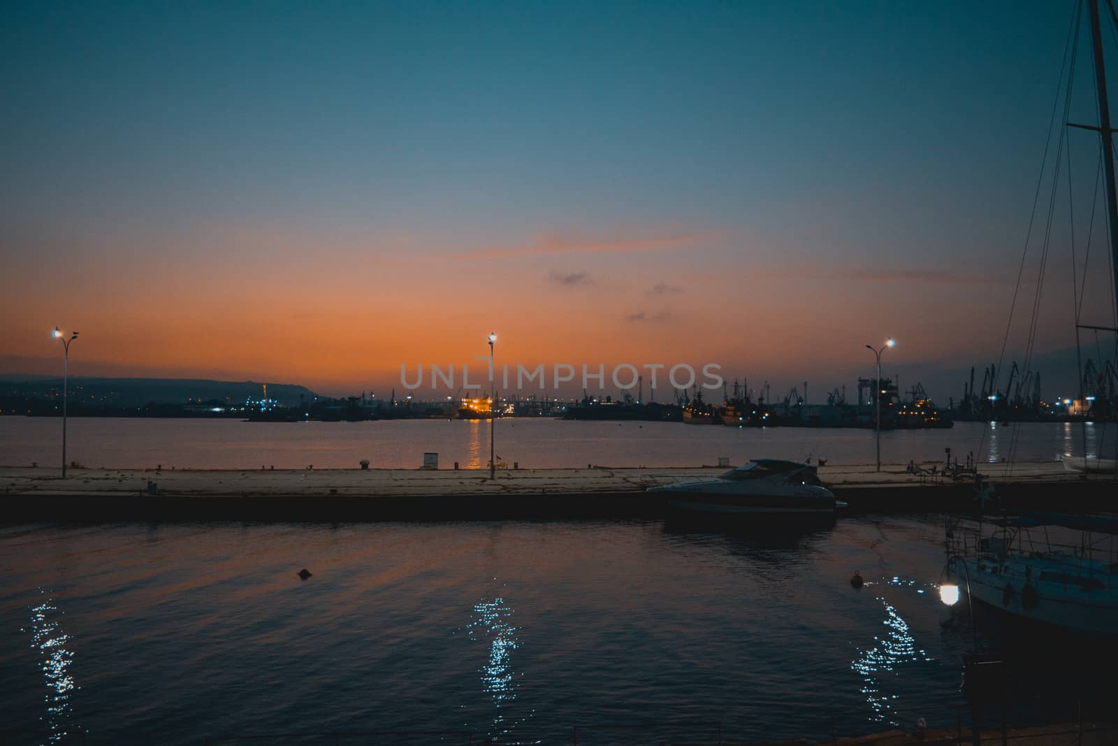 Sunset landscape combined with lights reflecting in the sea and some boats.