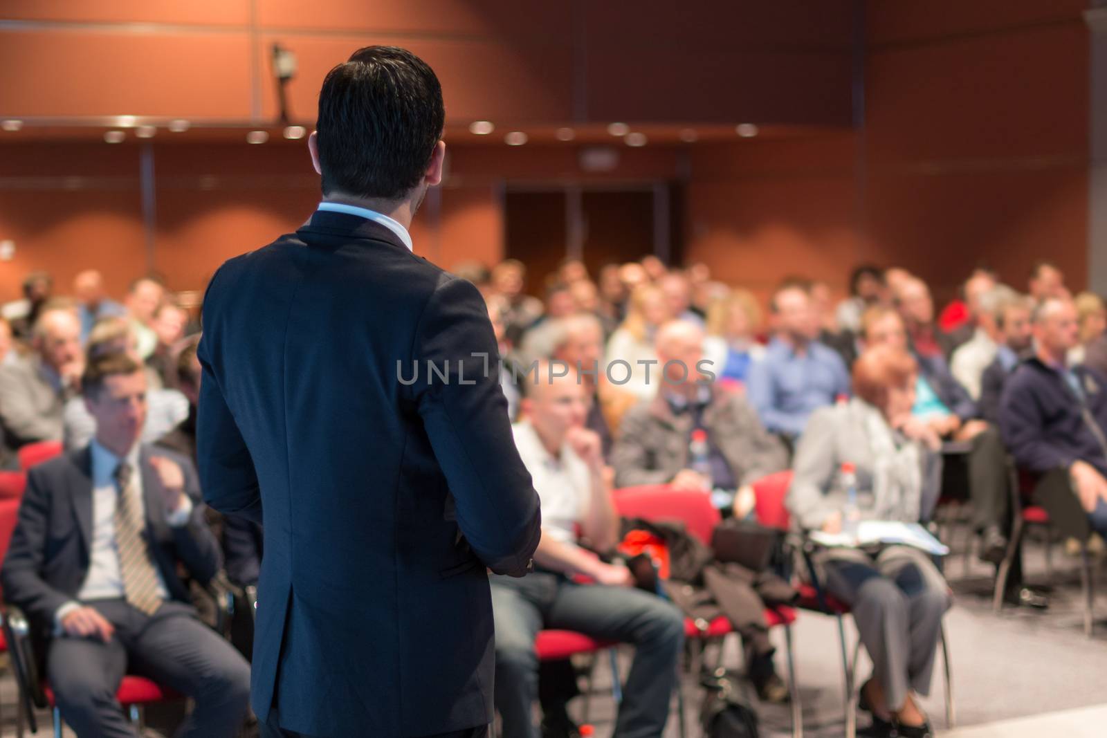 Speaker giving a talk on corporate business conference. Unrecognizable people in audience at conference hall. Business and Entrepreneurship event.