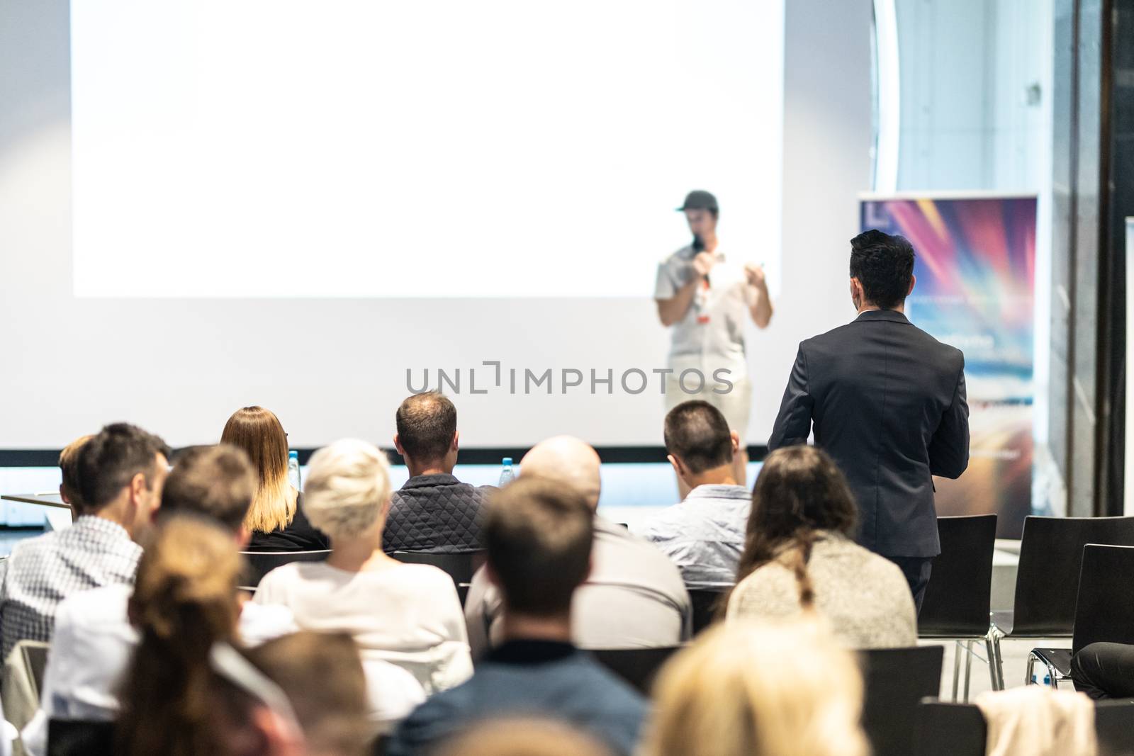 I have a question. Group of business people in conference hall. Businessman in audience standing and asking question to speeker. Conference and Presentation. Business and Entrepreneurship.