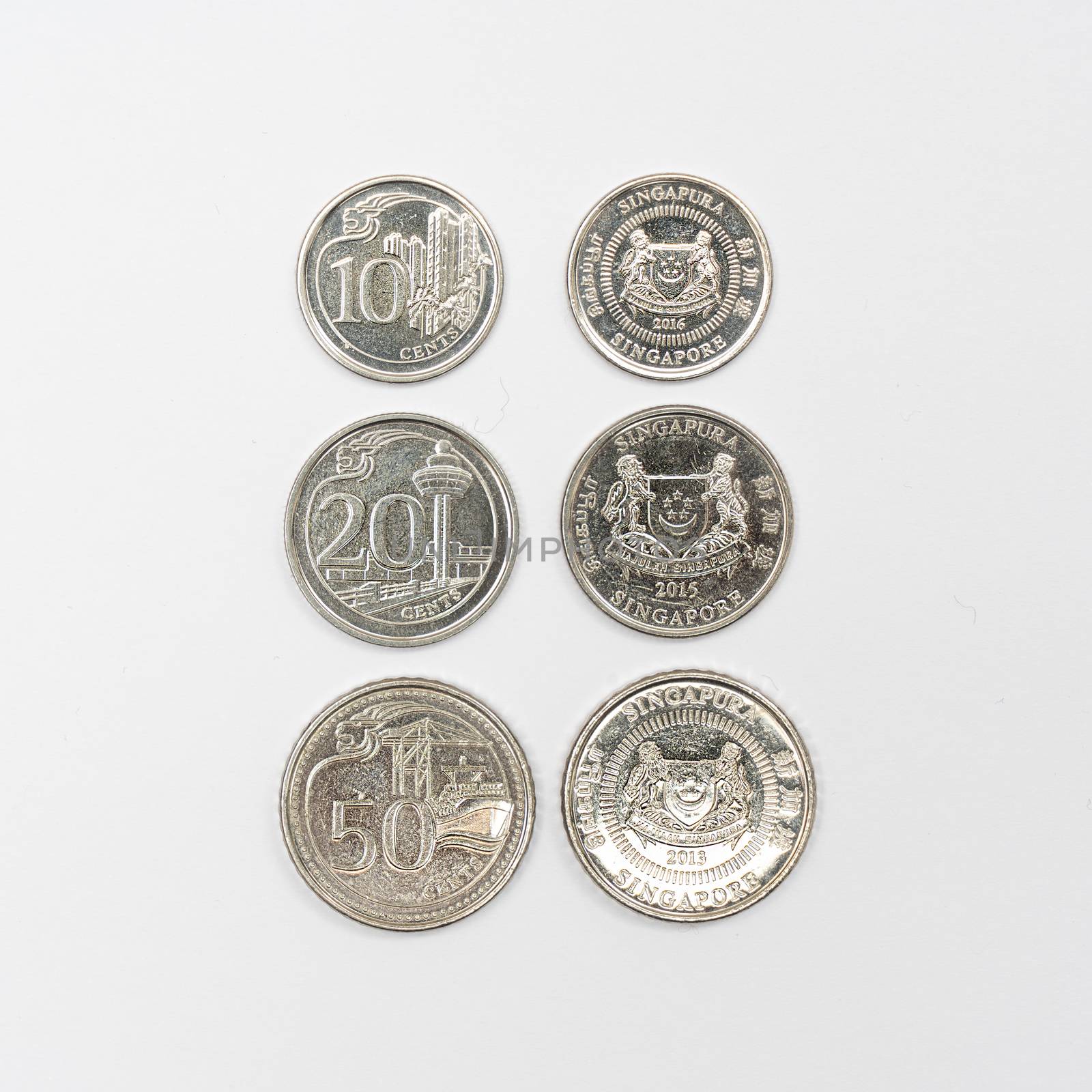 some Singaporean dollar coins on a white surface