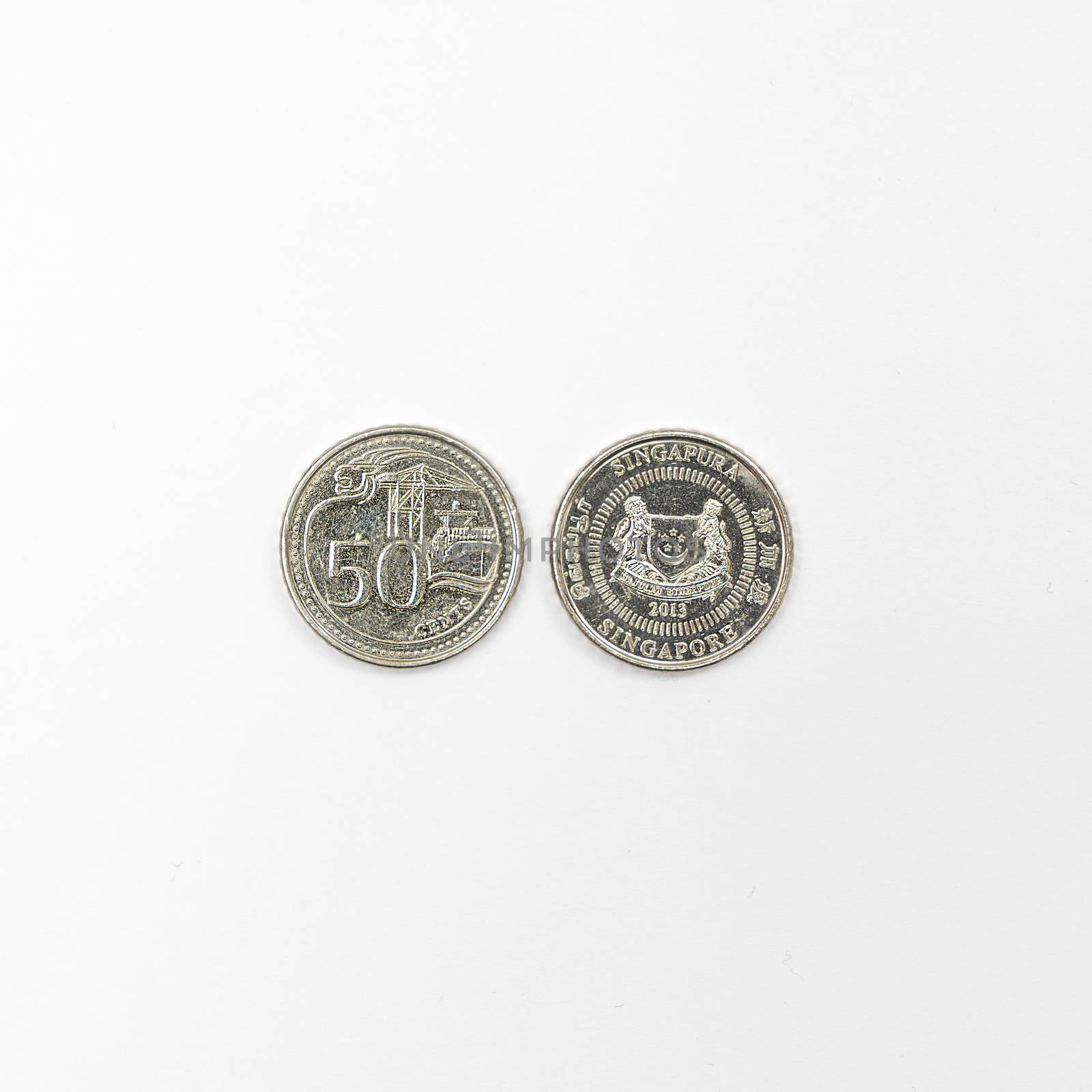 some Singaporean dollar coins on a white surface