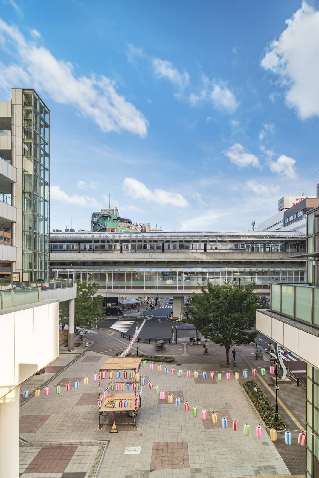 View of the square in front of the Nippori train station decorated for the Obon festival in the summer with a yagura tower and paper lanterns in the Arakawa district of Tokyo