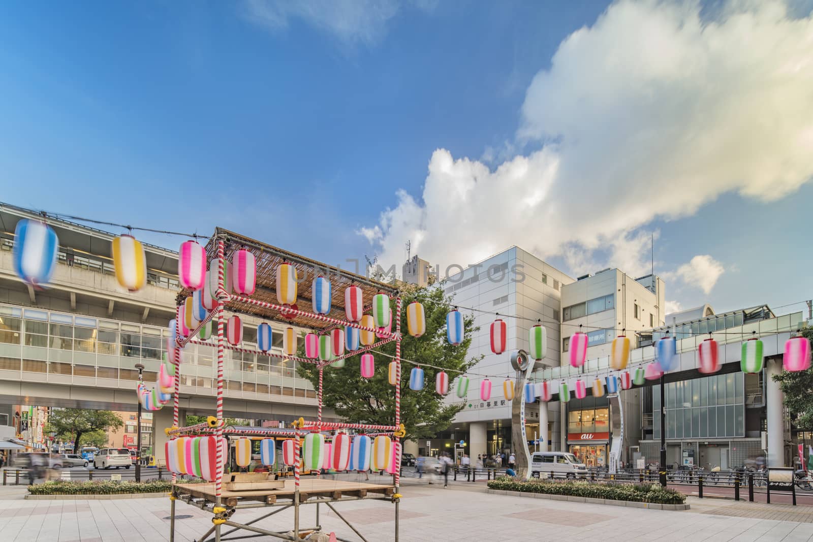 View of the square in front of the Nippori train station decorated for the Obon festival in the summer with a yagura tower and paper lanterns in the Arakawa district of Tokyo