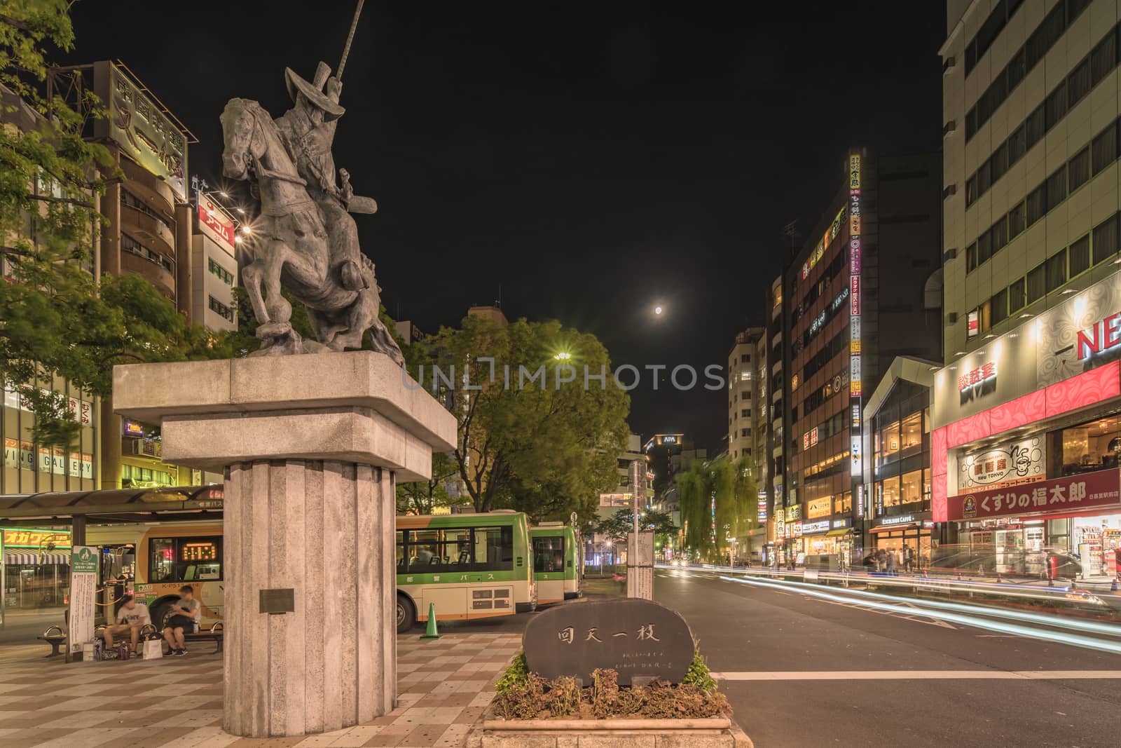 Night view of the square in front of the Nippori train station in the Arakawa district of Tokyo with a statue of a horse ridden by Ota Dokan who was a 15th century Japanese samurai warrior-poet, military tactician and Buddhist monk. Dōkan is best known as the architect and builder of Edo Castle, the actual Imperial Palace.