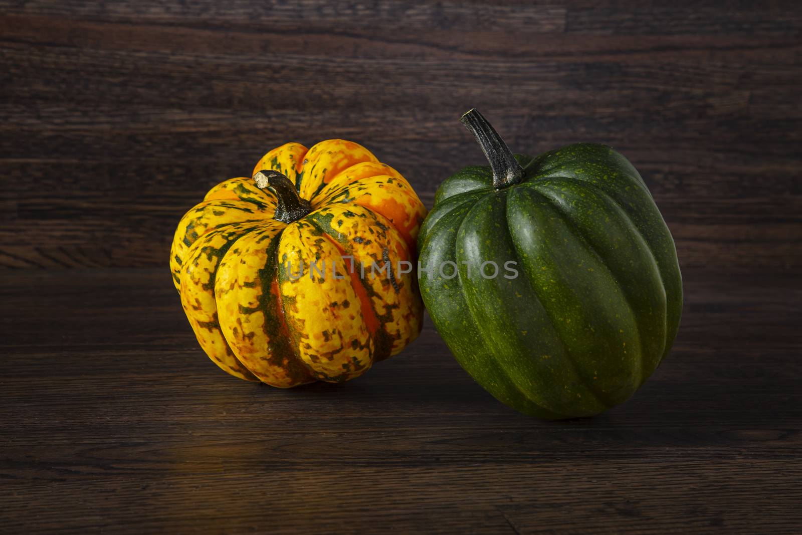 orange and green sweet dumpling squash against a dark wood background