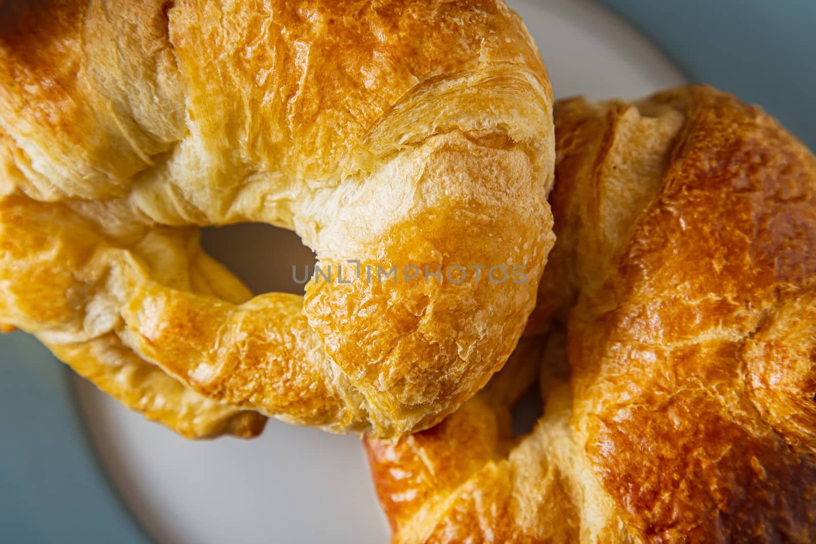 close up view of two croissants stake on top of one another on a blue rimmed plate