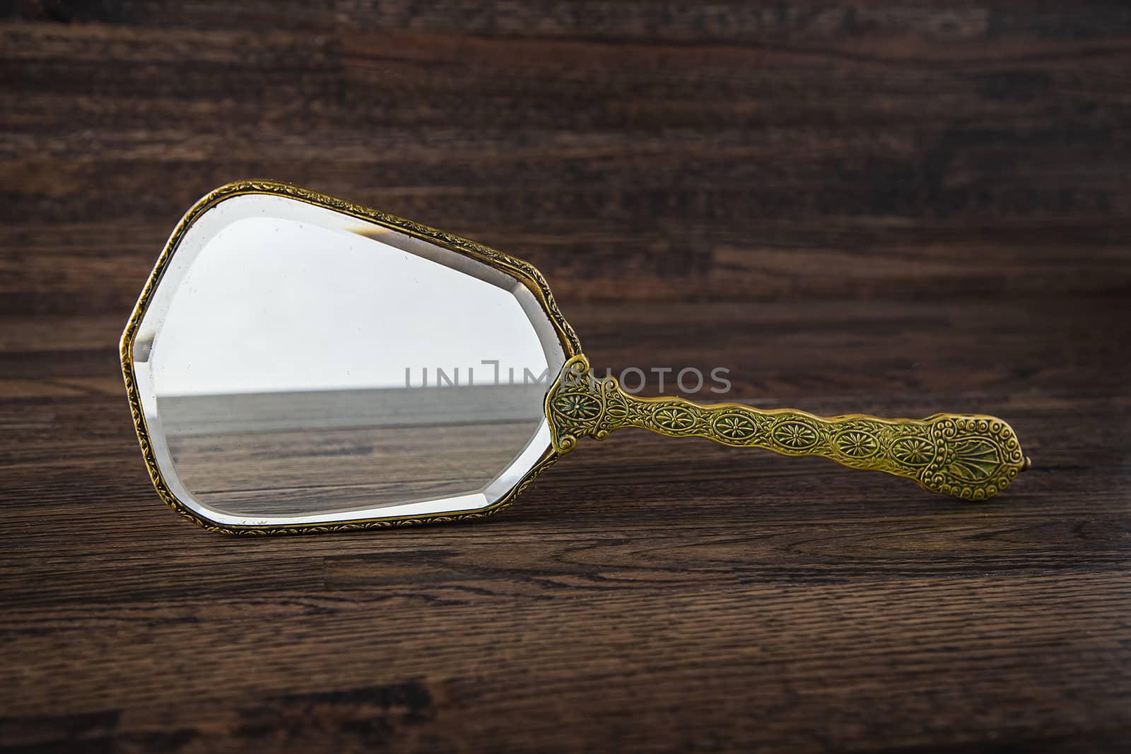 old vintage mirror standing on it’s side against a dark wood background