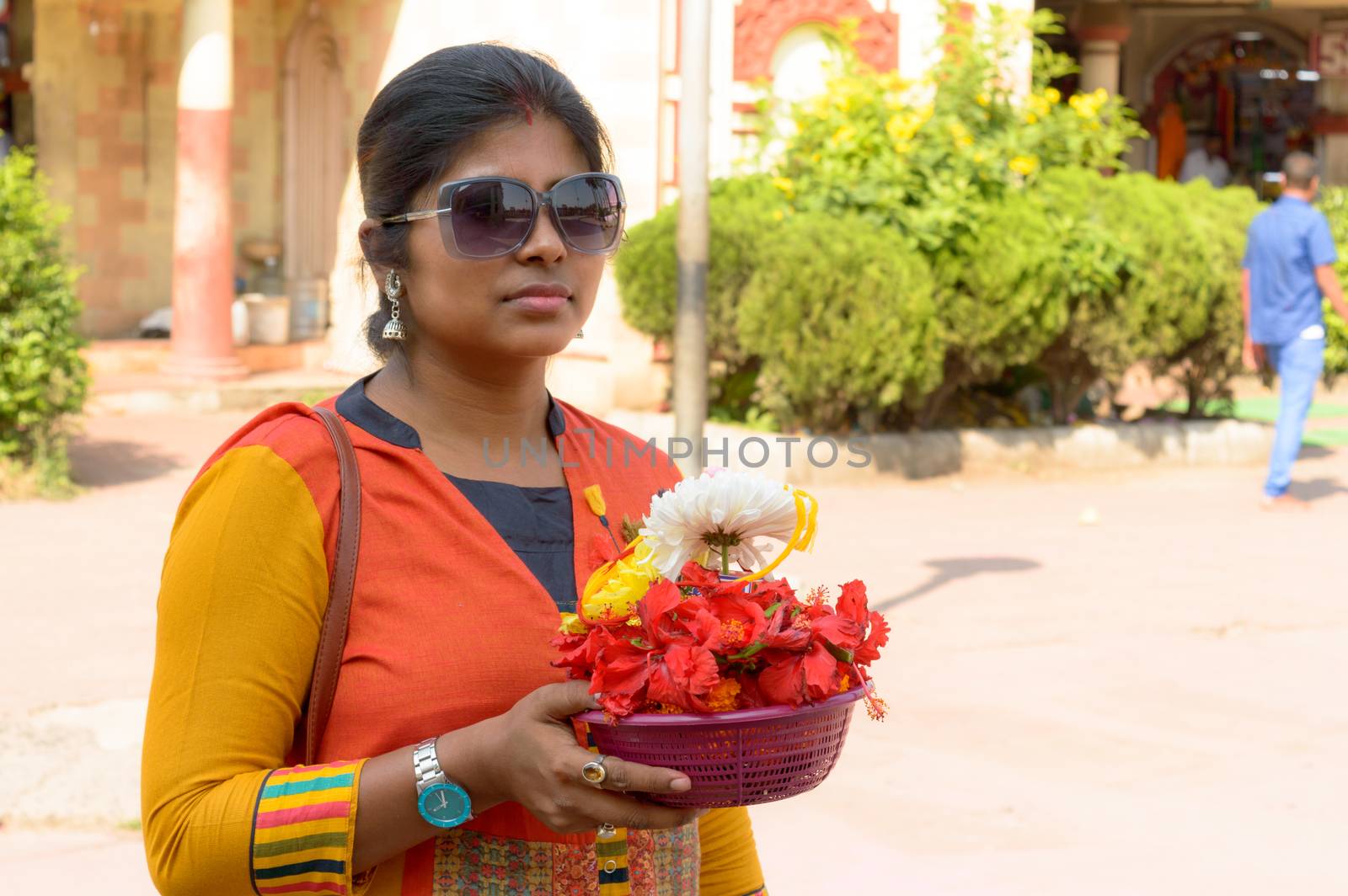 Smiling Portrait of beautiful young adult traditional Married Bengali woman holding a bucket of religious offering flowers during Durga puja celebration. Dakshineswar Kali Temple West Bengal India