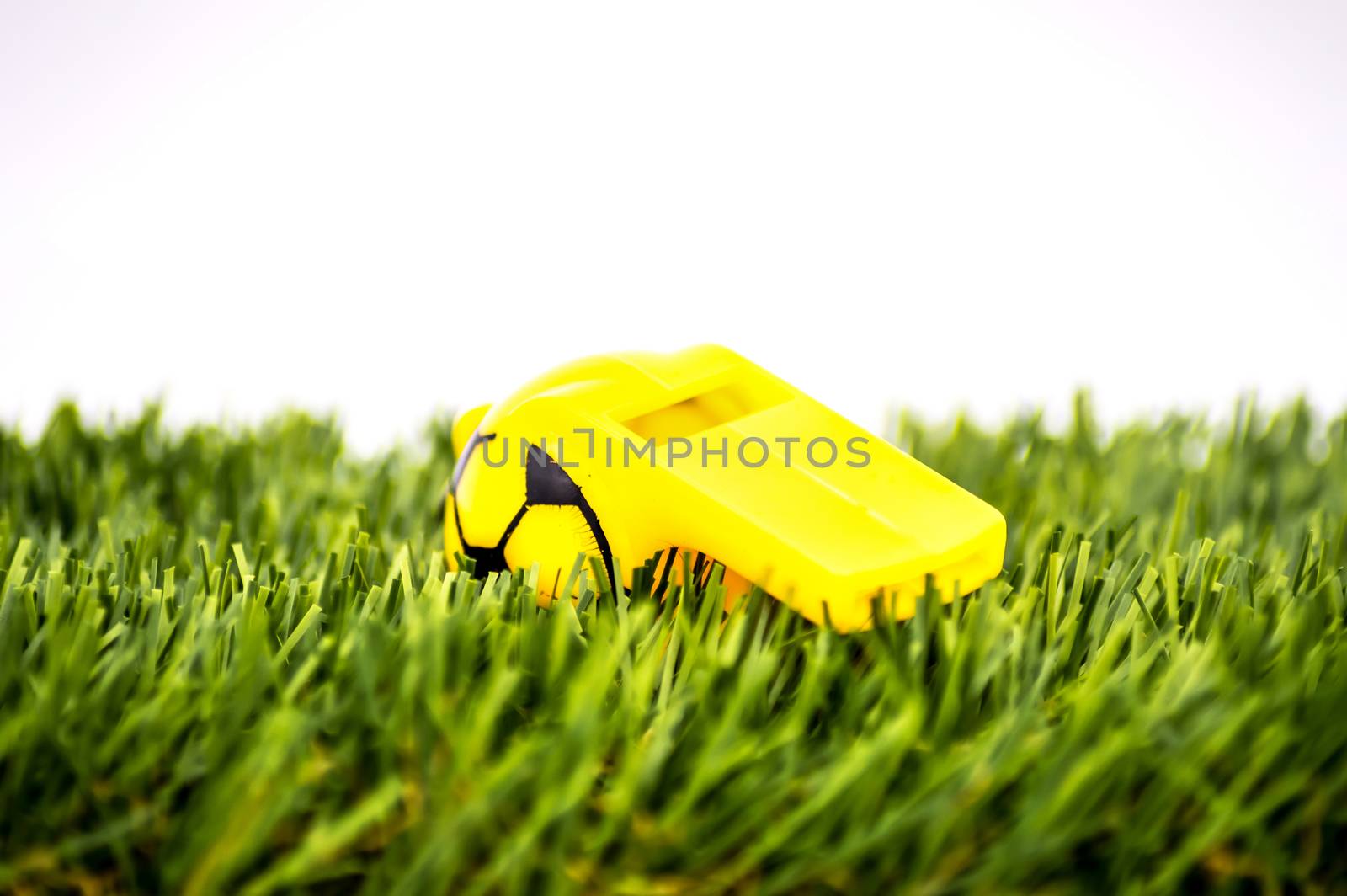 Yellow whistle soccer sports on grass background - penalty, foul or sport concept, selective focus