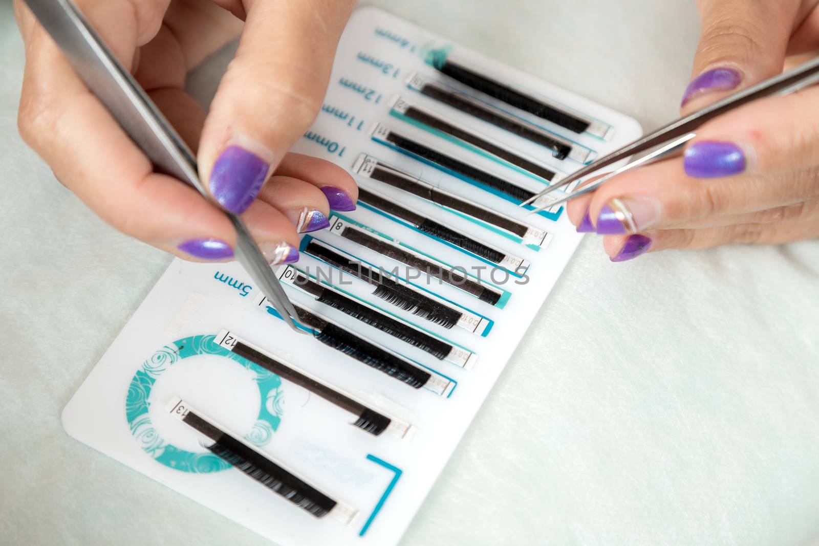 master lash maker is holding one false eyelash by tweezers in hand, close-up