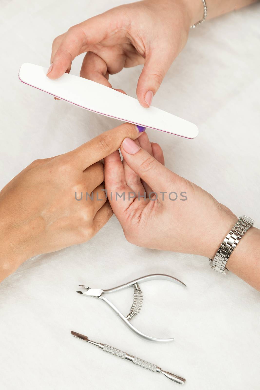 Woman in a nail salon receiving a manicure by a beautician with nail file. Nails manicure.