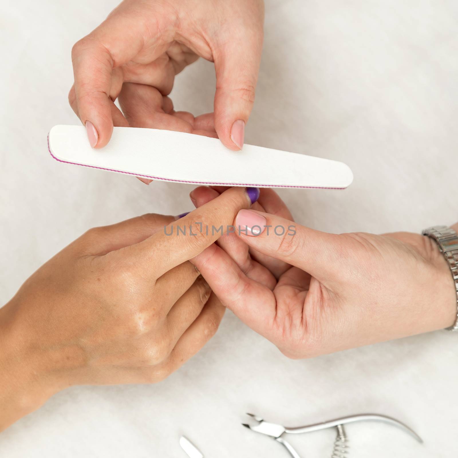Woman in a nail salon receiving a manicure by a beautician with nail file. Nails manicure.