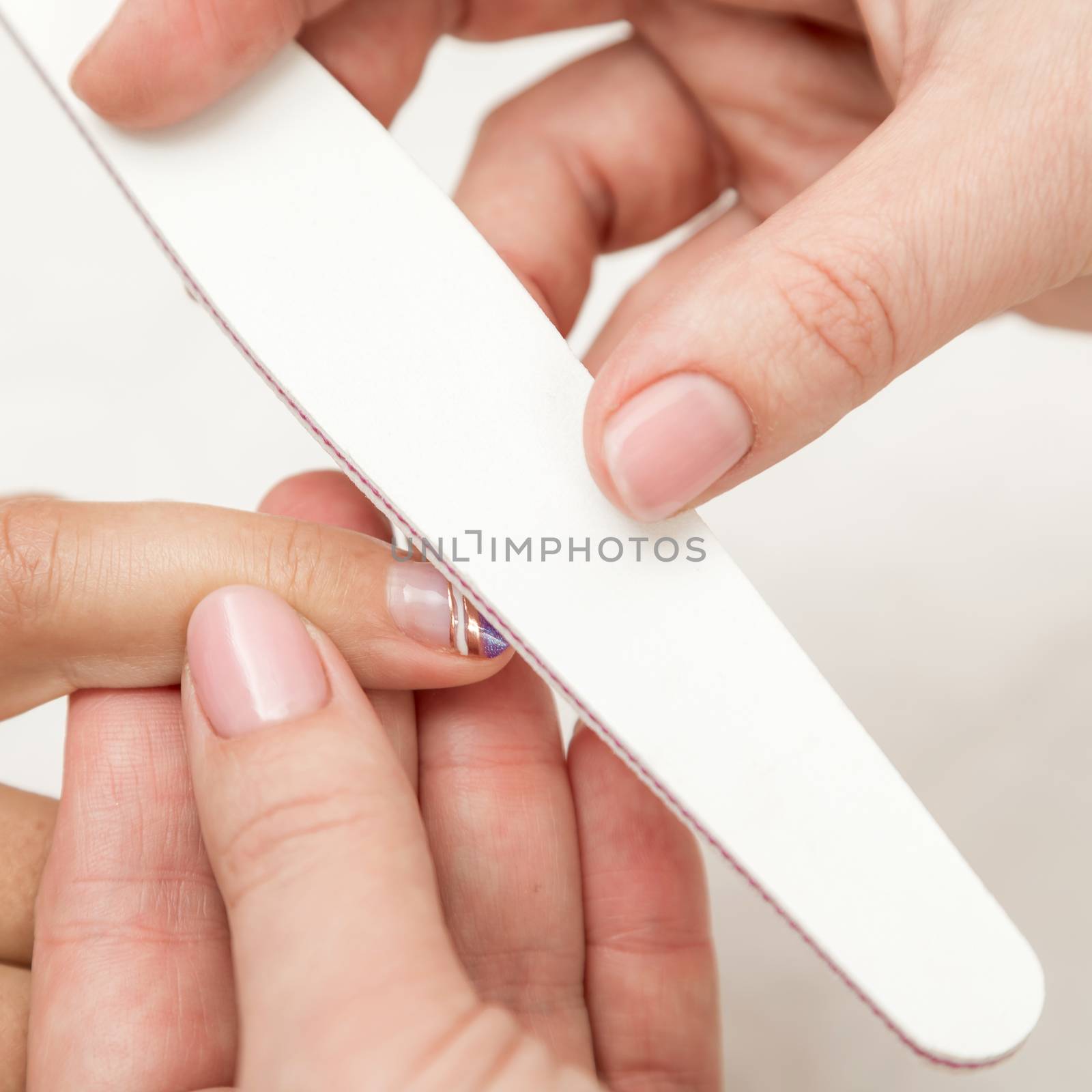 Woman in a nail salon receiving a manicure by a beautician with nail file. Nails manicure.