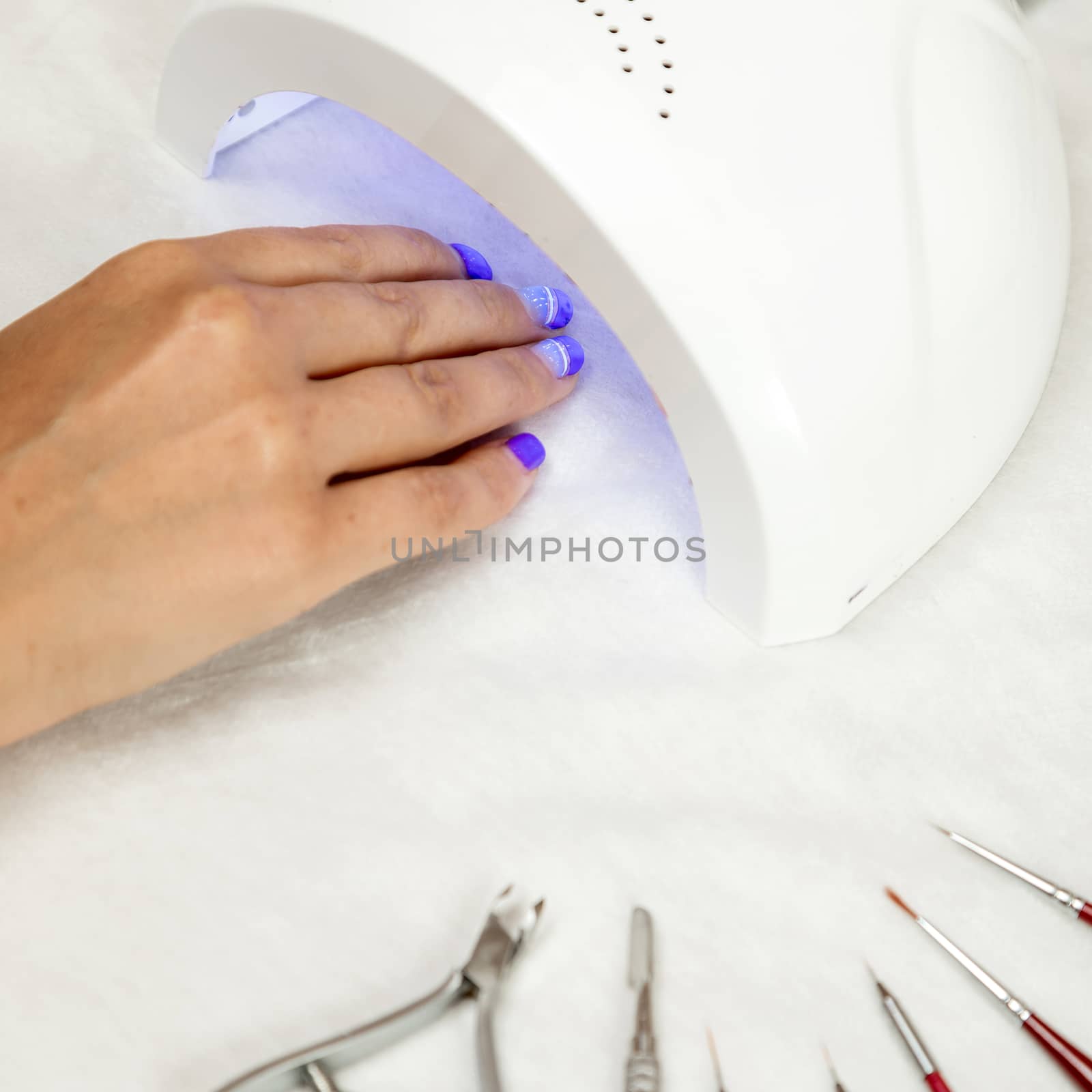 The woman 's hand lies in a UV lamp to dry the coating on the nails.