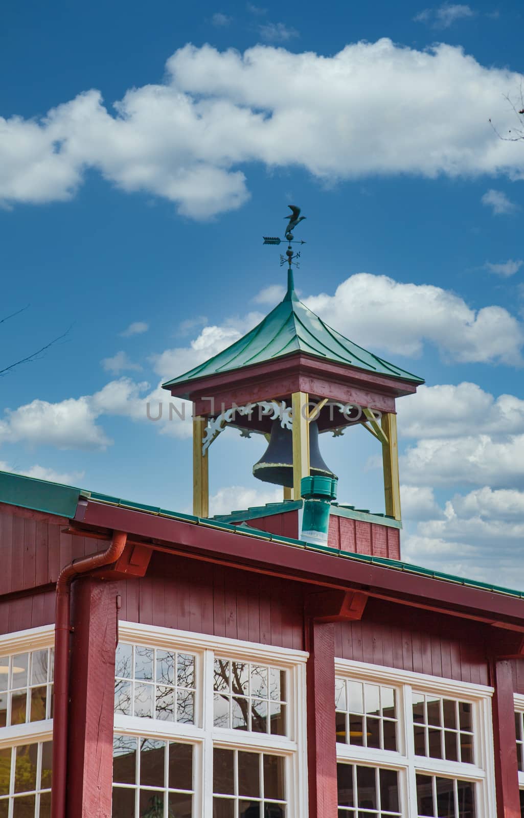 A traditional bell tower and windvane on an old red building