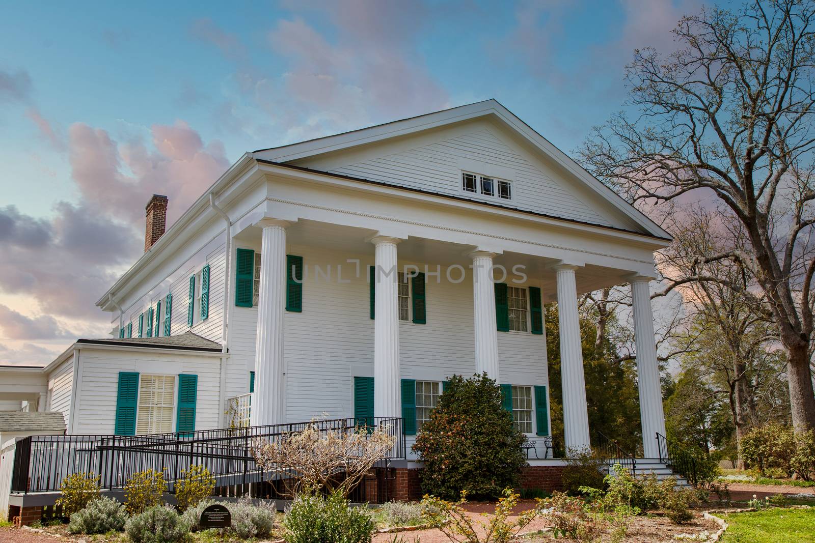 A white colonial home with columns on porch and a handicap accessibility ramp