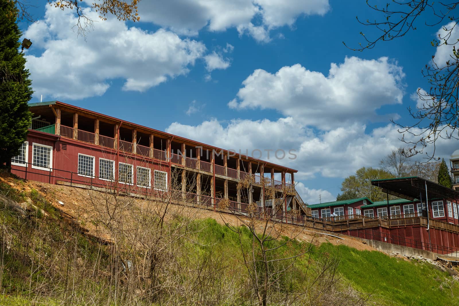 Old red farm buildings on top of a hill under nice blue sky with puffy clouds