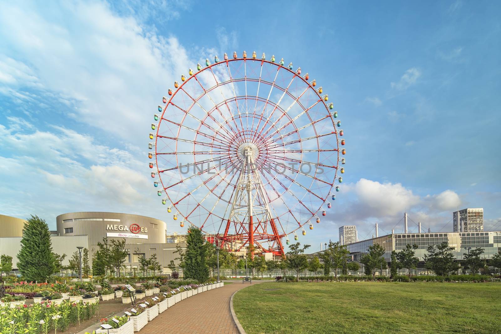 Odaiba colorful tall Palette Town Ferris wheel named Daikanransha visible from the central urban area of Tokyo in the summer blue sky. Passengers can see the Tokyo Tower, the twin-deck Rainbow Bridge, and Haneda Airport, as well as central Tokyo during their ride.