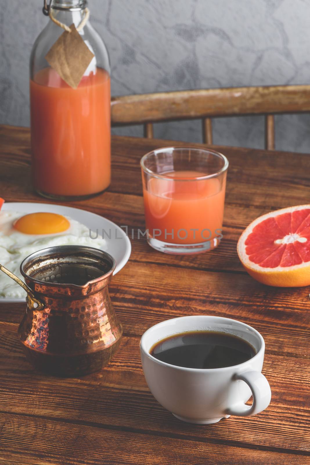 Breakfast with turkish coffee, fried eggs, juice and fruits over wooden table