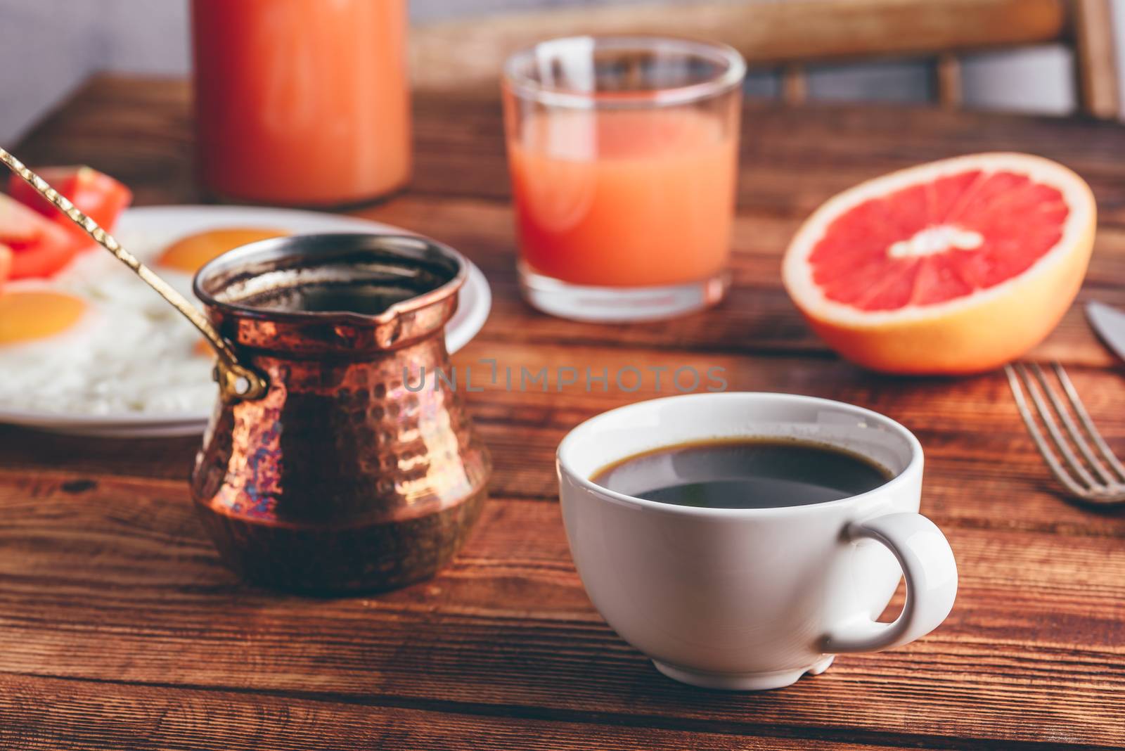 Breakfast with turkish coffee, fried eggs, juice and fruits over wooden table