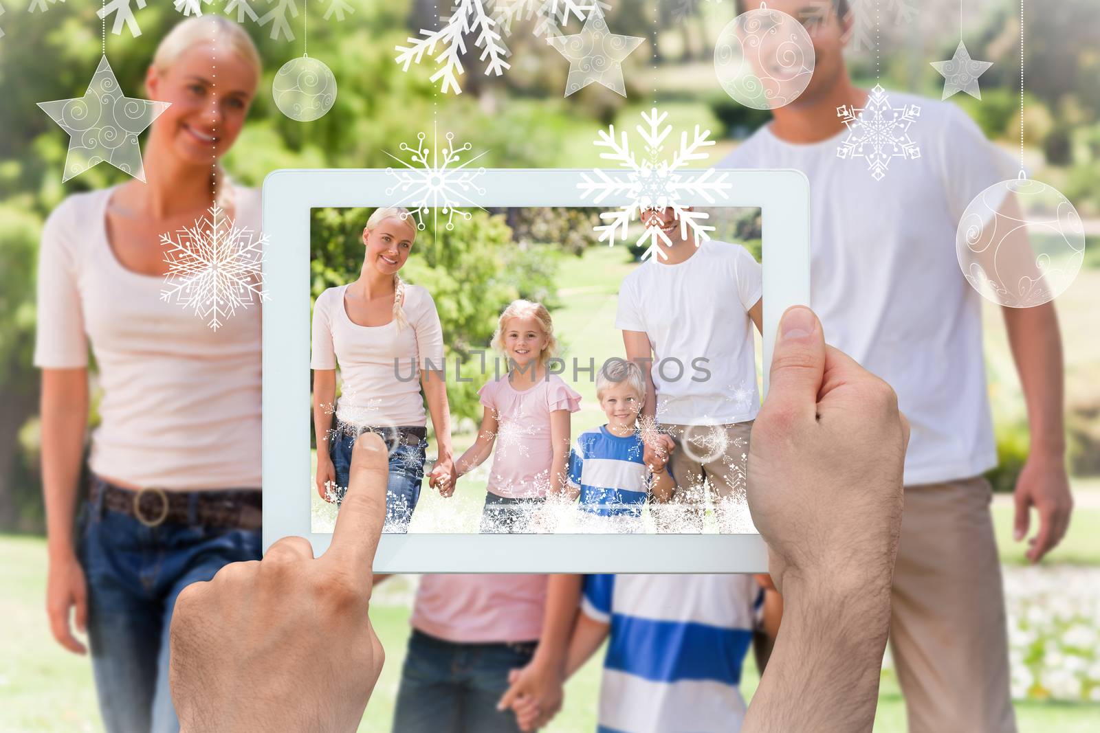 Hands holding tablet pc against adorable family during the summer 