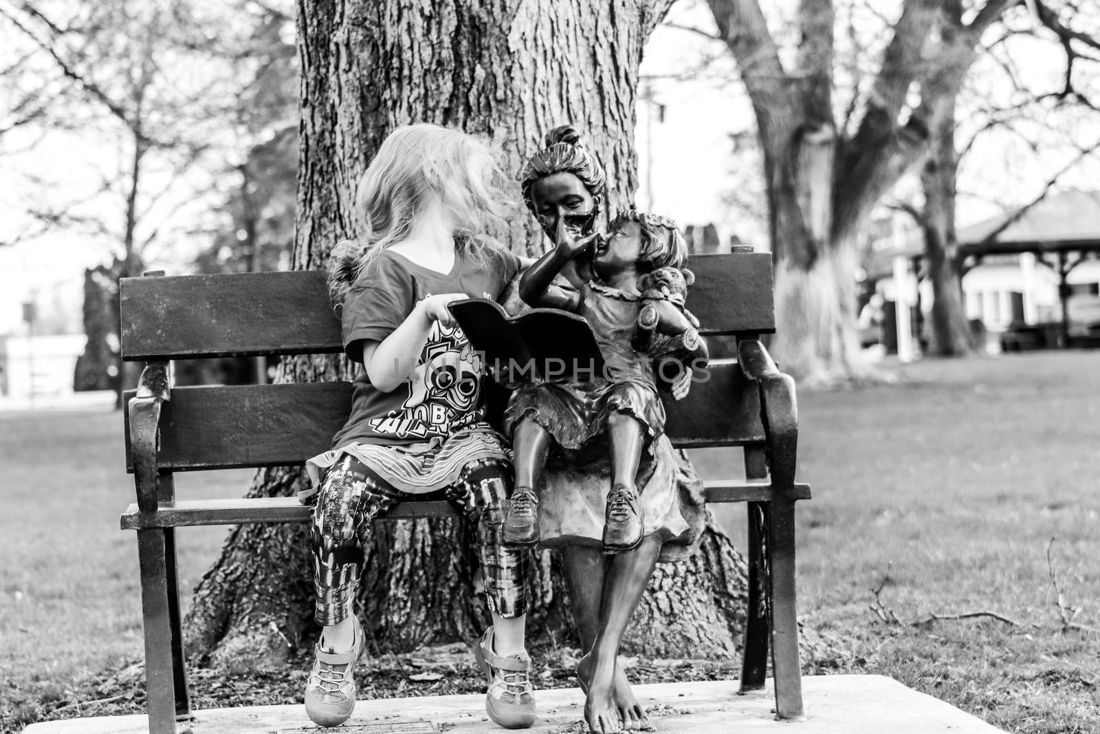 A little girl sitting on a bench in a park. High quality photo