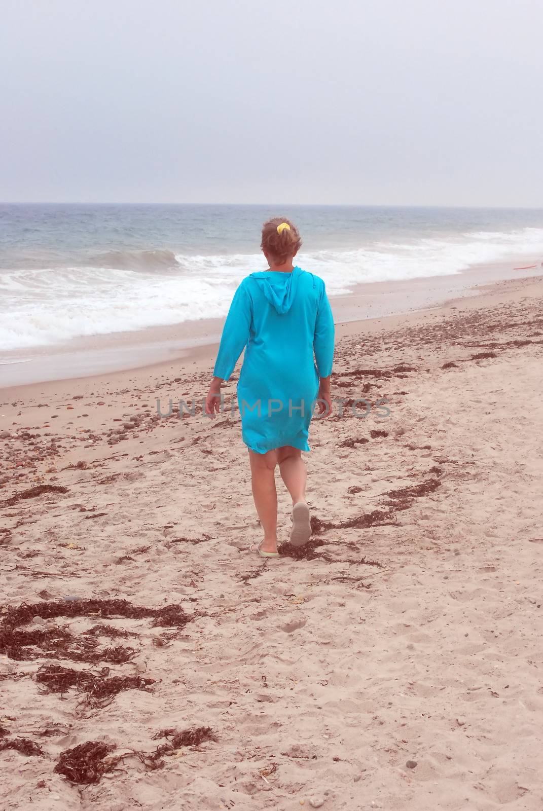 Mature female beauty walking in the sand on the beach outside.