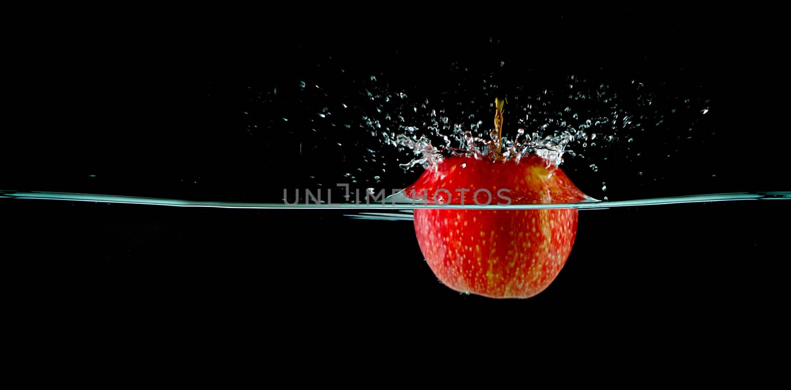 Apple splash in water with black background. Water shooting up into the air