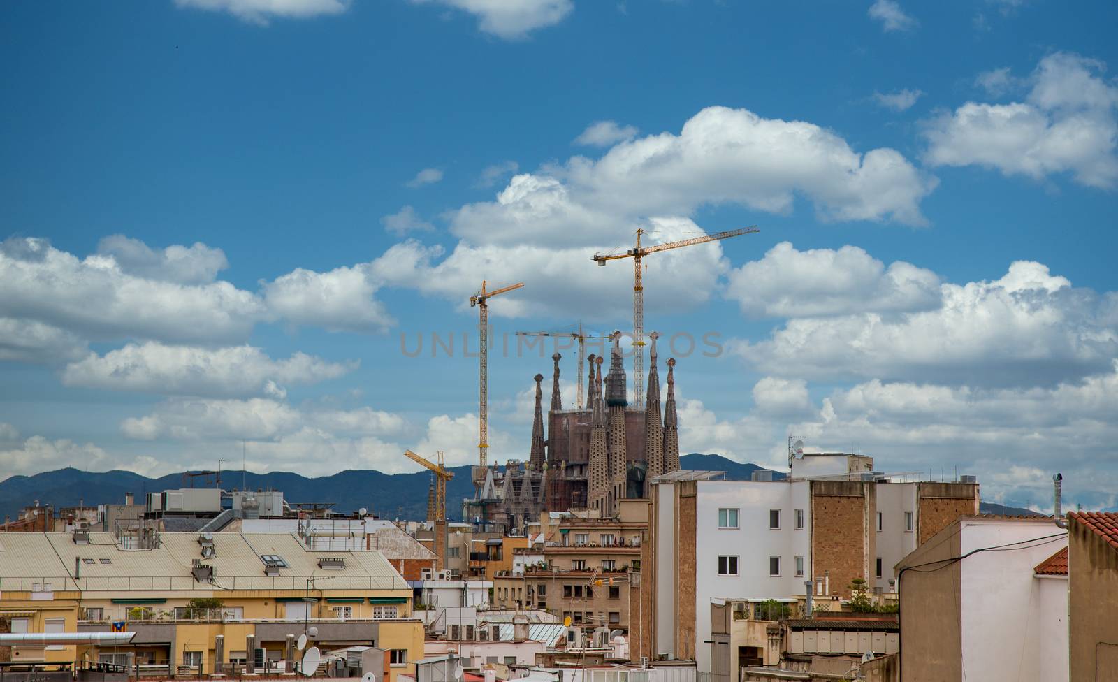 Old church under construction with cranes beyond skyline of Barcelona