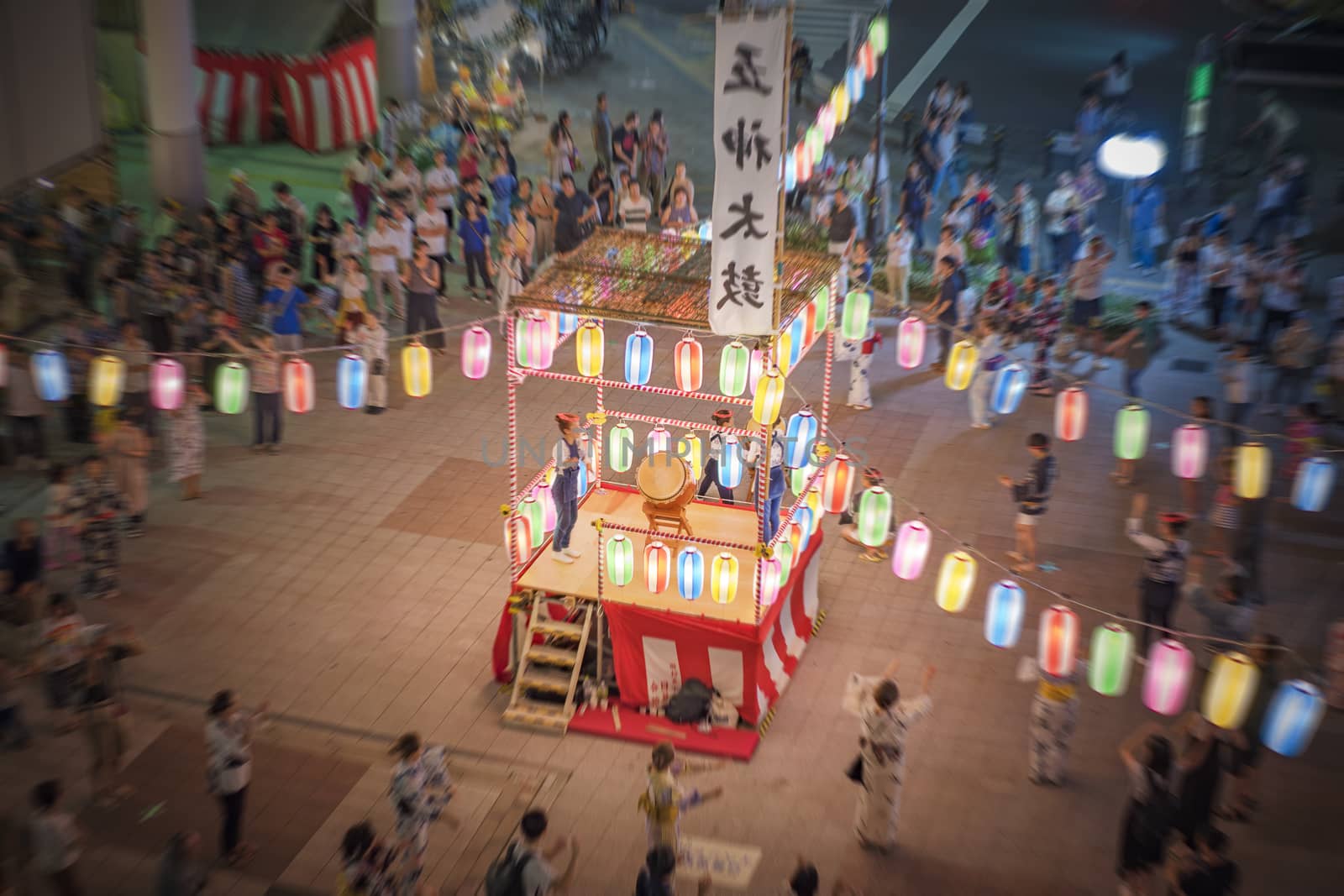 View of the square in front of the Nippori train station decorated for the Obon festival with illuminated paper lanterns  in the summer night with a yagura tower and paper lanterns in the Arakawa district of Tokyo.
